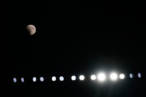 A partial lunar eclipse is seen above the stadium lights during the second half of a preseason NFL football game between the New England Patriots and Cleveland Browns Thursday, Aug. 27, 2026, in Cleveland. (AP Photo/Carolyn Kaster)