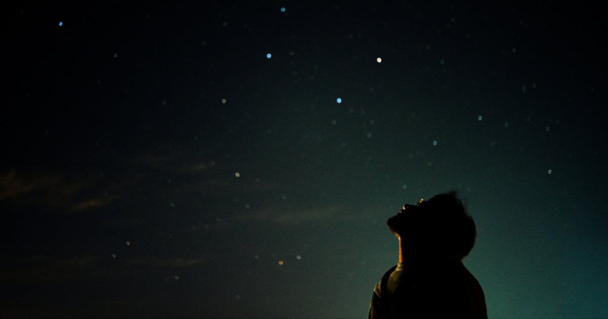 A man looking up at night sky watching stars. (Representative Cover Image Source: Getty Images | MAREVGENNA)