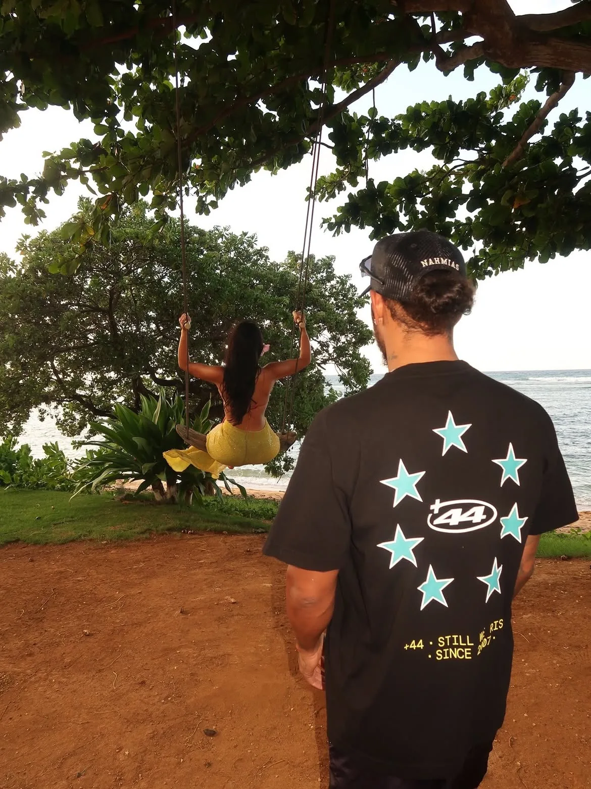 Kim Kardashian sits on a swing as Lewis Hamilton admires the view