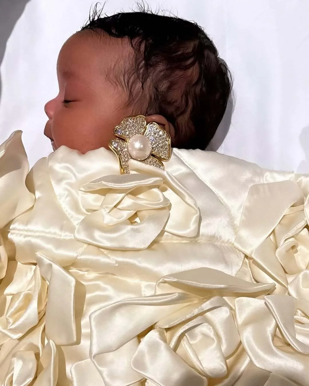 Infant Rocki sleeps wrapped in satin and pearls