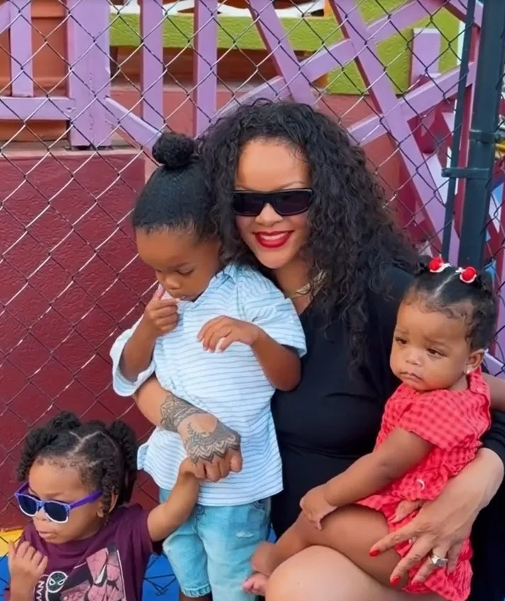 Rihanna holds Riot and RZA close and carries Rocki in her arms