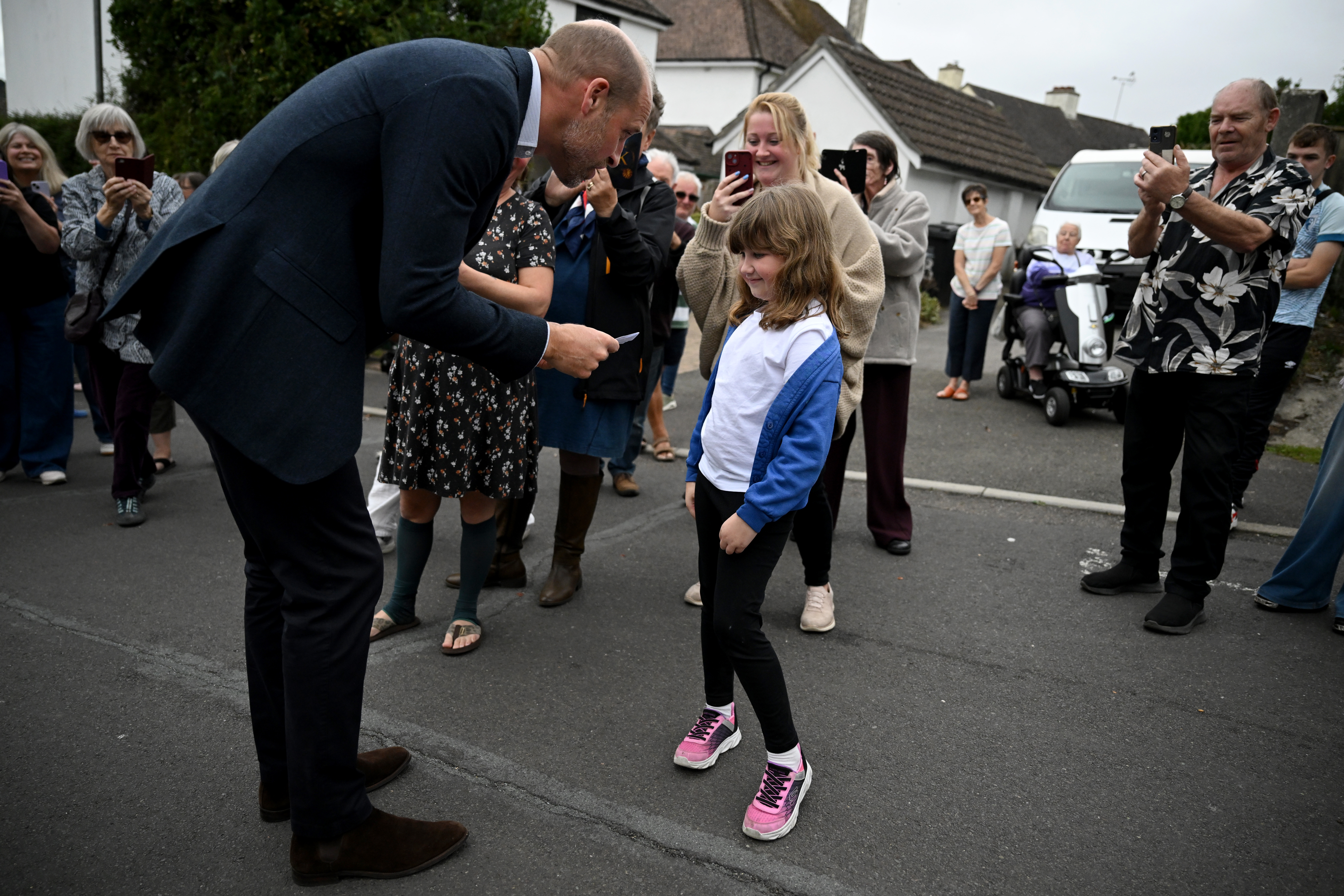 ILMINSTER, ENGLAND - OCTOBER 06: Prince William, Prince of Wales receives a card for Princess Charlotte from a young well wisher during his visit to Ilminster Fire Station on October 06, 2026 in Ilminster, England. The Prince of Wales visited Ilminster in Somerset to learn about communities growing their resilience to wild fires, flood and challenges caused by extreme weather and global warming. (Photo by Finnbarr Webster/Getty Images)