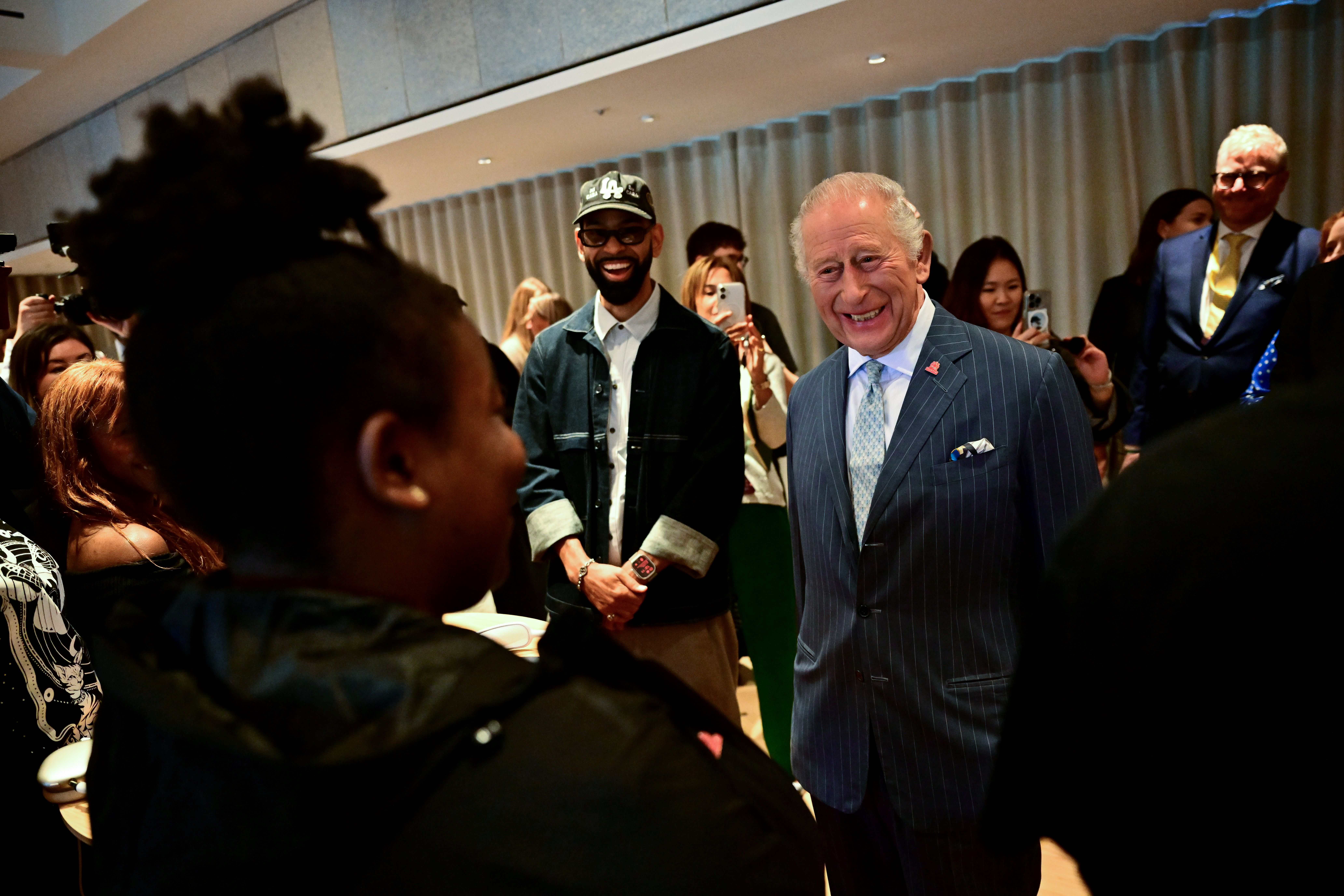 LONDON, ENGLAND - OCTOBER 7: King Charles III smiles as he meets a mentor during a music workshop for young people, the first as part of the Apple x King's Trust Creative Labs, at Battersea Power station on October 7, 2026 in London, England. (Photo by Ben Stansall - WPA Pool/Getty Images)