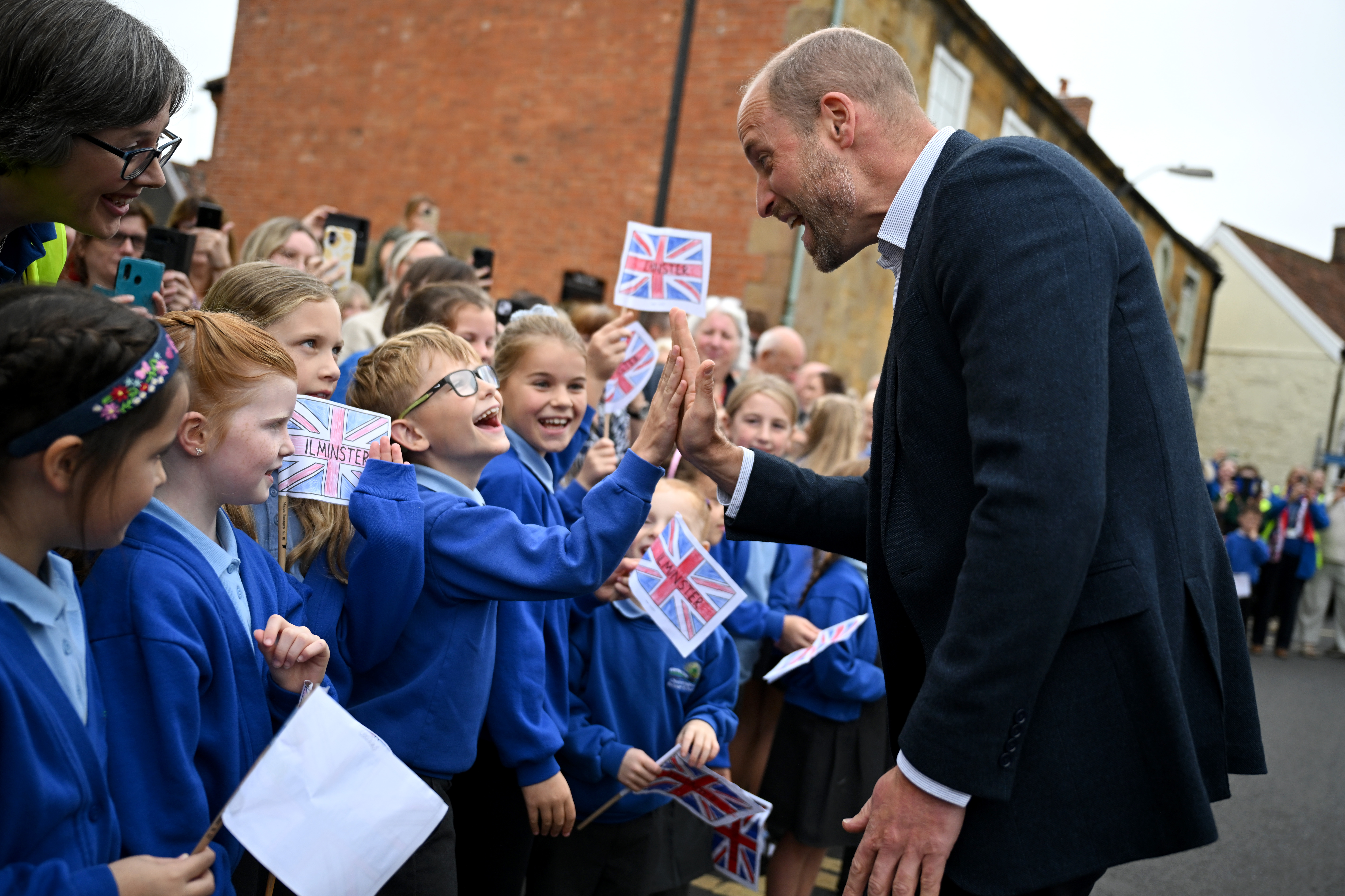 Prince William, Prince of Wales, high-fives members from the local school during his visit to Sweet Surprise cafe on October 06, 2026 in Ilminster, England (Photo by Finnbarr Webster/Getty Images)