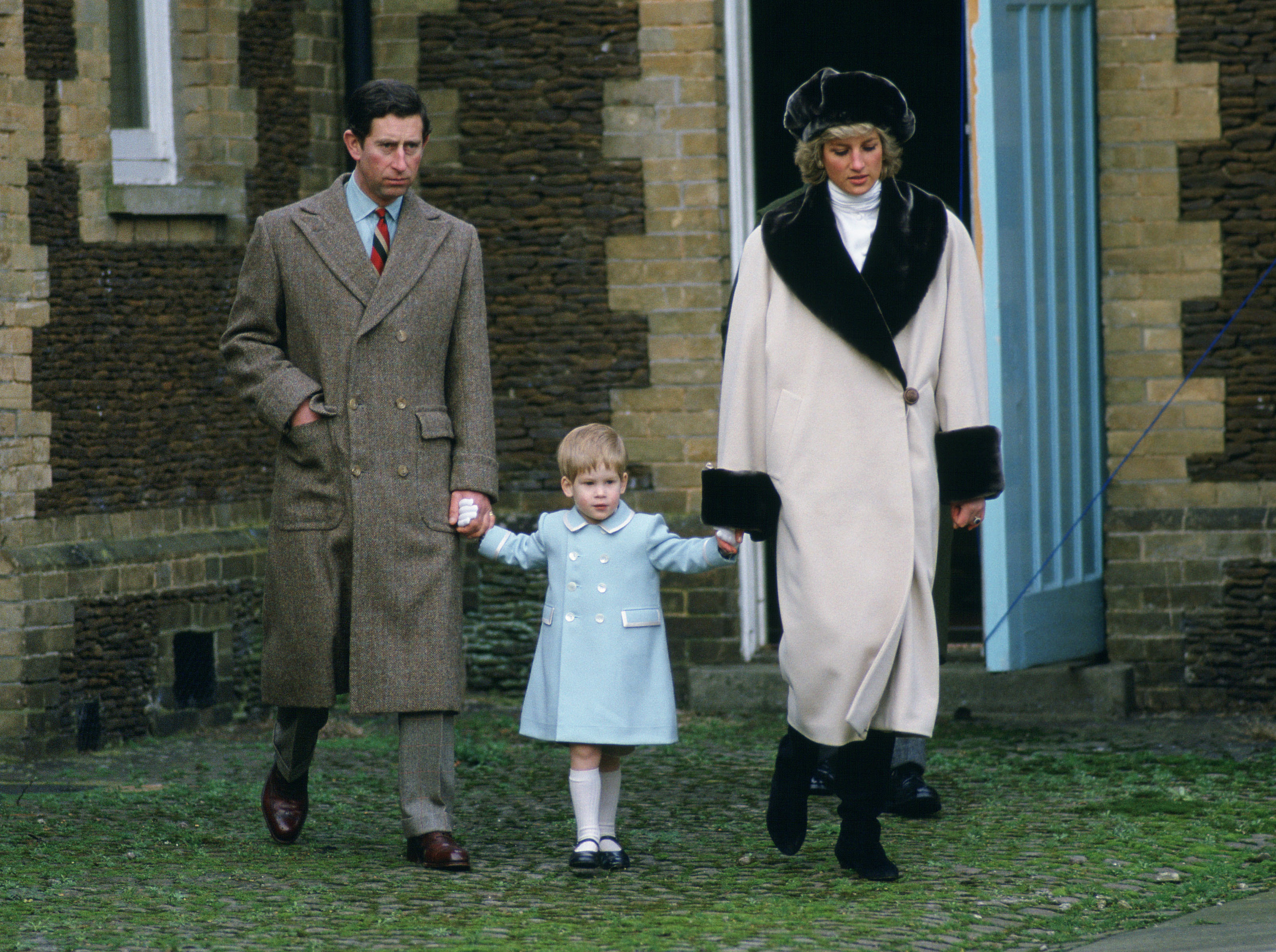SANDRINGHAM, UNITED KINGDOM - JANUARY 03:  Prince Charles, Prince Harry And Princess Diana Holding Hands As They Arrive For A Photocall At Sandringham.  She Is Wearing Cashmere And Wool Coat With Synthetic Beaver Fur By Fashon Designer Arabella Pollen And A Fake Fur Hat By Milliner Gilly Forge.  Prince Harry's Coat Designed By Fashion Designer Catherine Walker  (Photo by Tim Graham Photo Library via Getty Images)