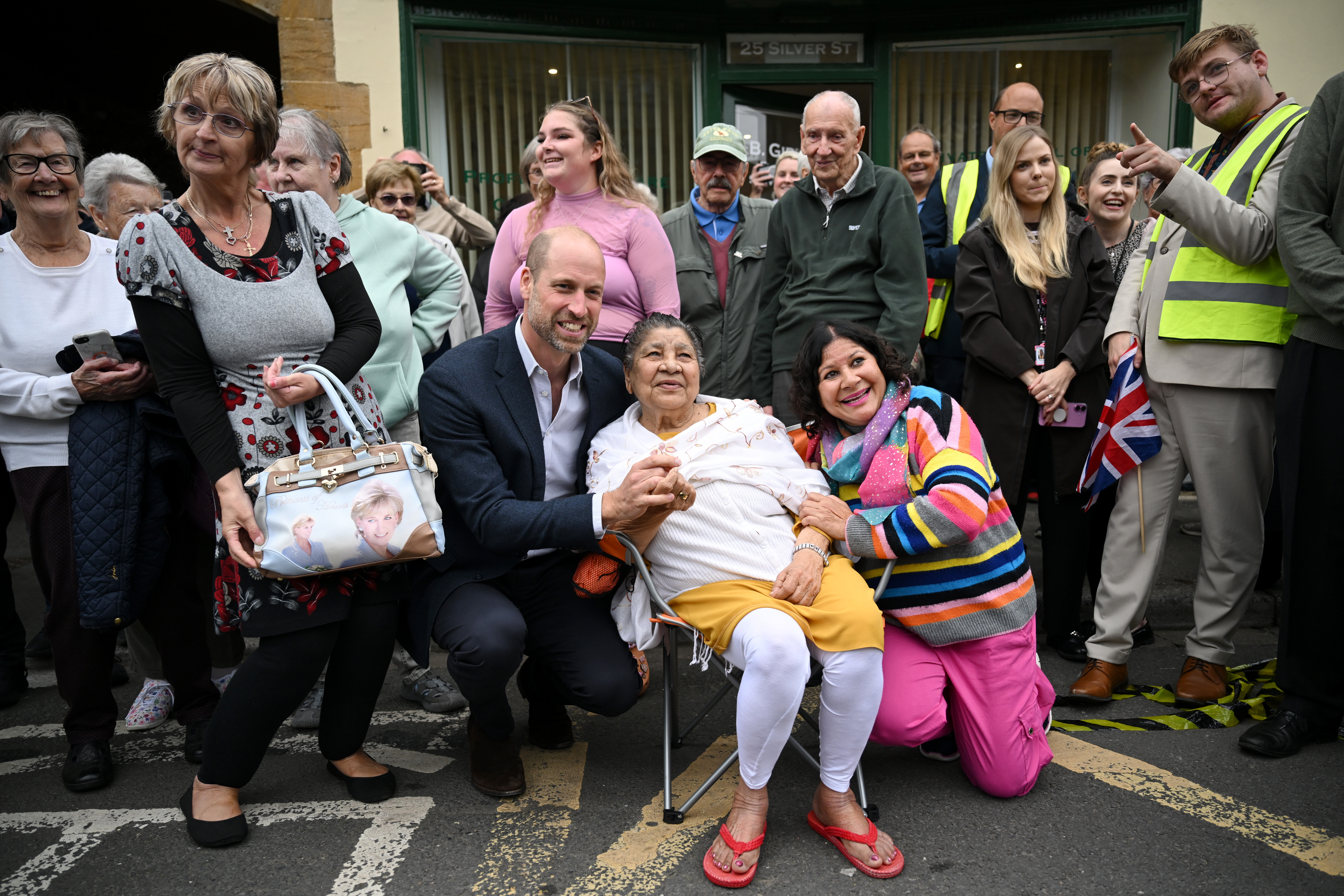 ILMINSTER, ENGLAND - OCTOBER 06: Prince William, Prince of Wales poses with locals during his visit to Sweet Surprise cafe on October 06, 2026 in Ilminster, England. The Prince of Wales visited Ilminster in Somerset to learn about communities growing their resilience to wild fires, flood and challenges caused by extreme weather and global warming. (Photo by Finnbarr Webster/Getty Images)