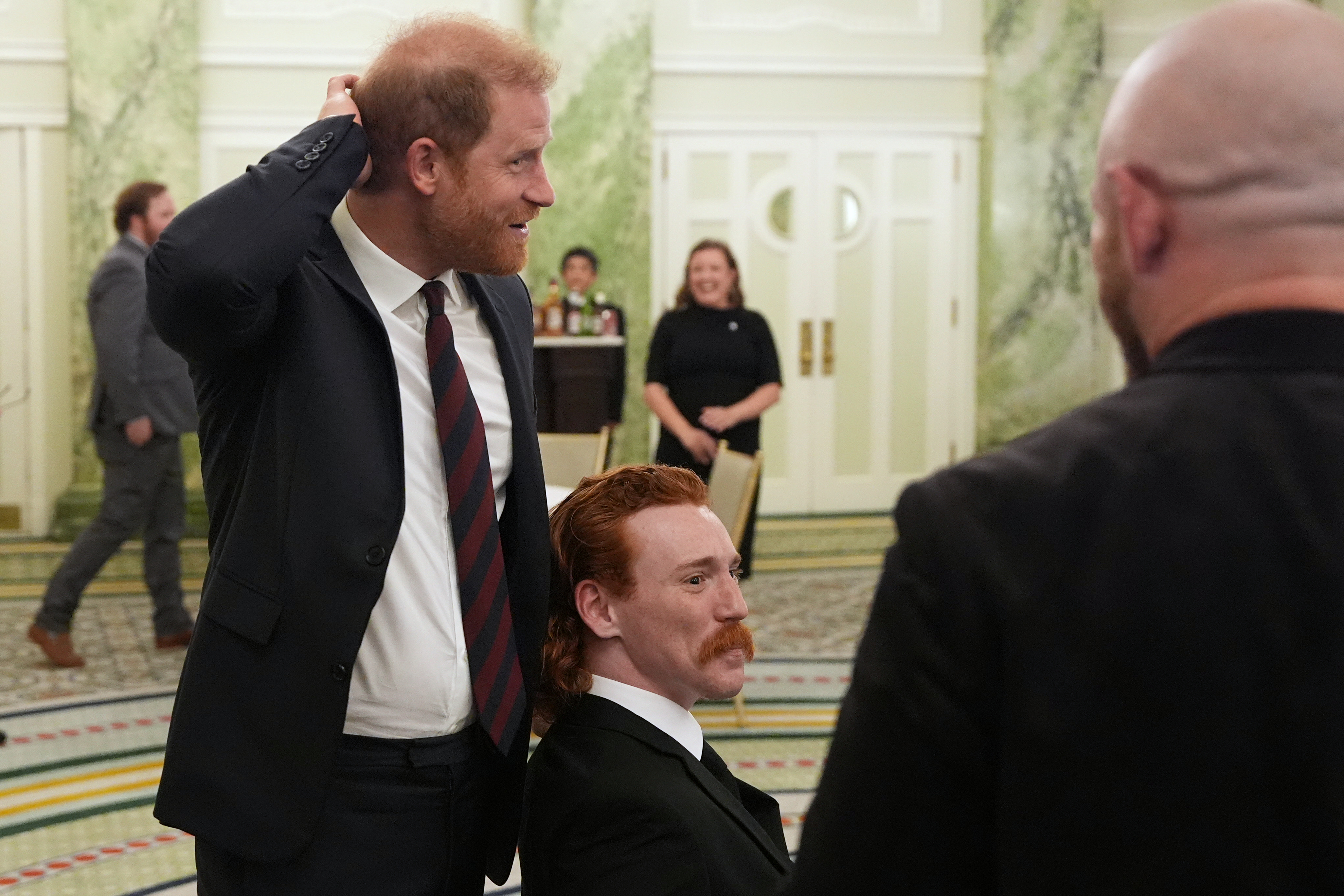 Britain's Prince Harry, the Duke of Sussex, talks about red hair with William Bringer as he arrives to speak at a roundtable about support for veterans, Wednesday, Aug. 19, 2026, in Washington. (Image Source: AP Photo | Alex Brandon)