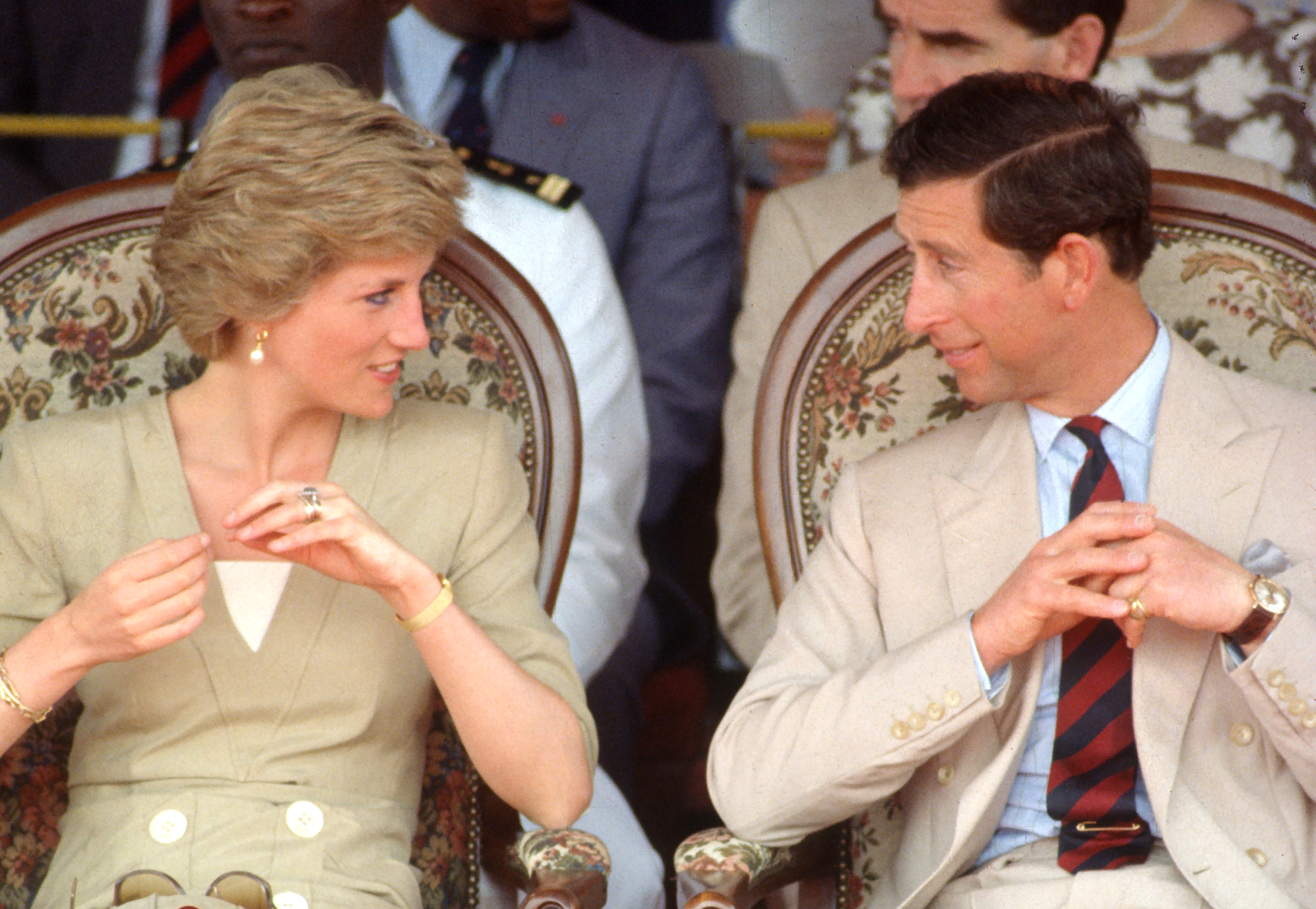 BAMENDA, CAMEROON - MARCH 22: Prince Charles, Prince of Wales and Diana, Princess of Wales, wearing a beige coloured dress designed by Catherine Walker, speak to each other as they attend a dancing display at the Bamenda Electrification Plant on March 22, 1990 in Bamenda, Cameroon. (Photo by Anwar Hussein/Getty Images)