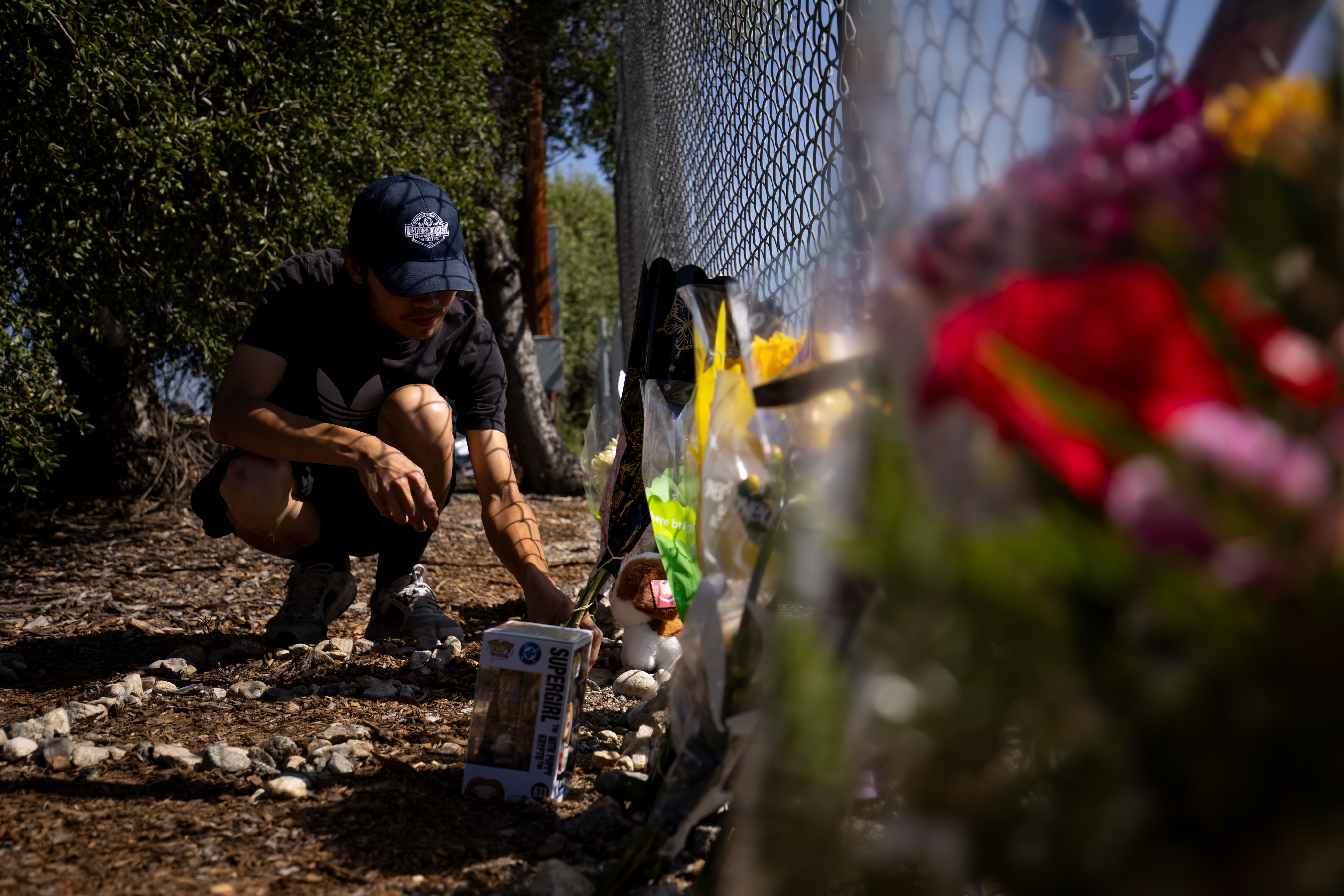 A person adjusts flowers at a memorial for Eliana Moreno and George Marciniw who died in a helicopter crash is at the site where their helicopter used to park at Whiteman Airport in Los Angeles, Wednesday, Sept. 16, 2026. (AP Photo/Ethan Swope)