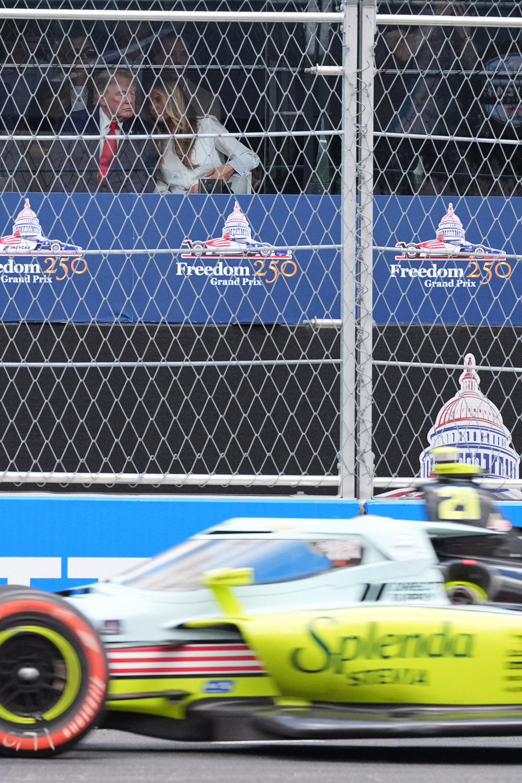 President Donald Trump and first lady Melania Trump watch the IndyCar Freedom 250 Grand Prix auto race in Washington, Sunday, Aug. 23, 2026 as driver Christian Rasmussen (21) of Denmark passes. (AP Photo/Alex Brandon)
