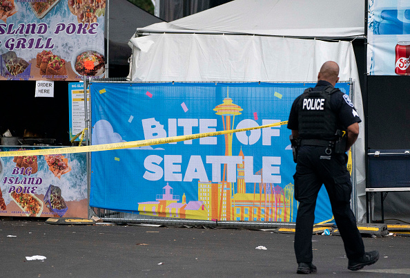 SEATTLE, WASHINGTON - JULY 26: A police officer walks by police tape and a sign for the Bite of Seattle event after a mass shooting at the event on July 26, 2026 in Seattle, Washington. At least two people are dead and at least five are wounded after a mass shooting at the event at Seattle Center. (Photo by David Ryder/Getty Images)