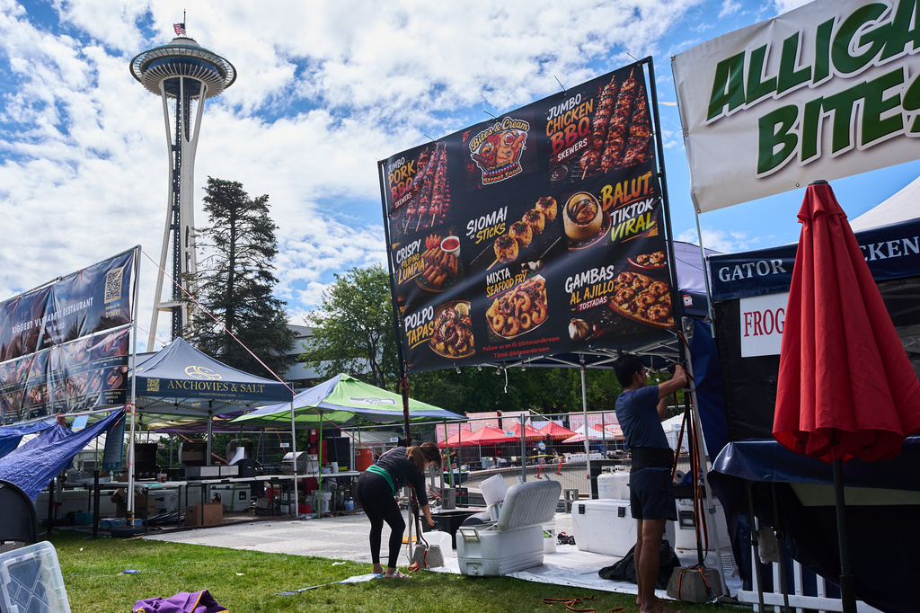Vendors break down signage the day after a shooting at Seattle Center during the Bite of Seattle food festival, Monday, July 27, 2026, in Seattle. (AP Photo/Lindsey Wasson)