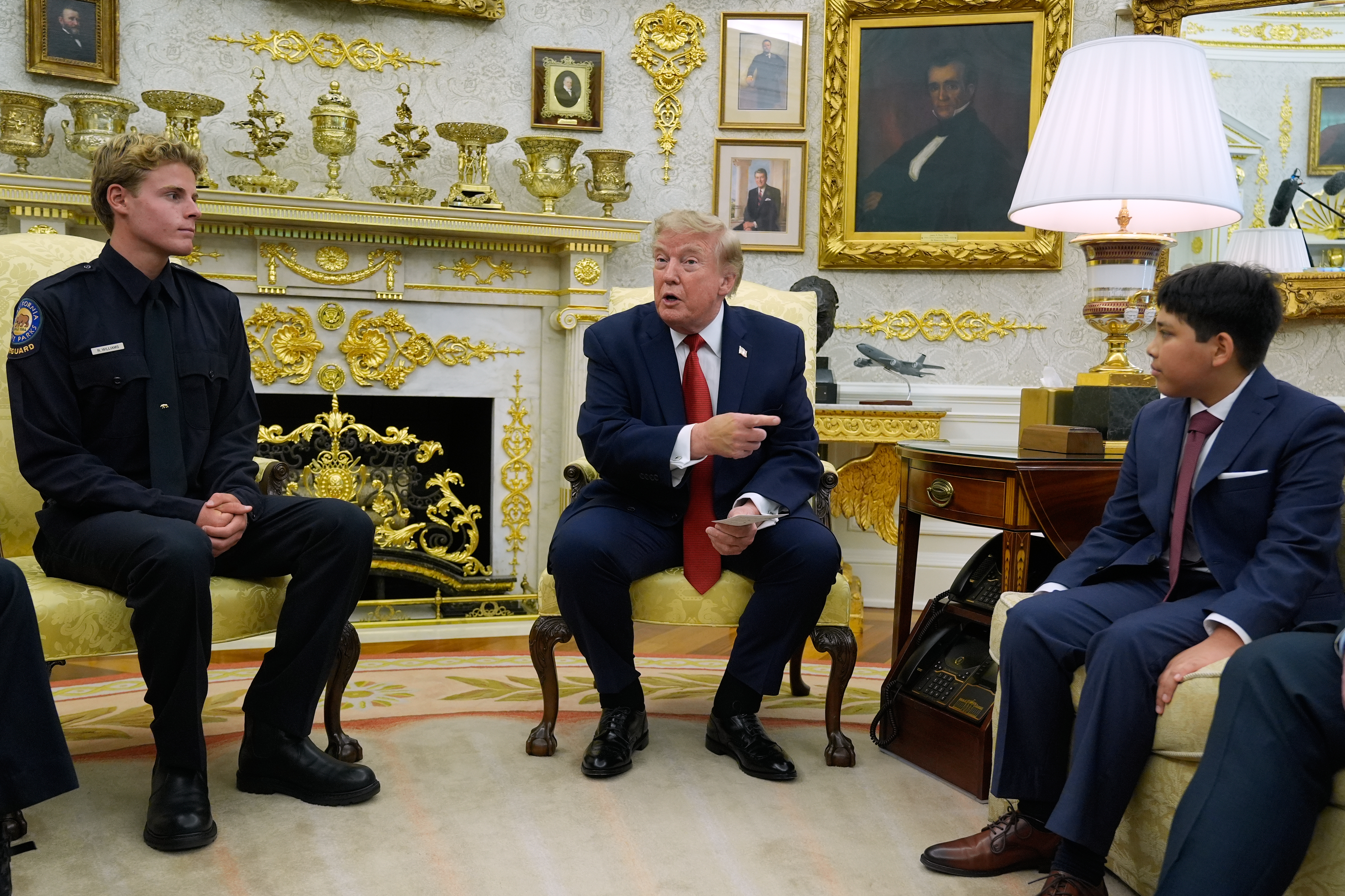 President Donald Trump gestures to Nathaniel Rai, the boy lifeguard Ryder Williams, left, saved as they meet in the Oval Office of the White House, Monday, Aug. 17, 2026, in Washington. (AP Photo/Manuel Balce Ceneta)