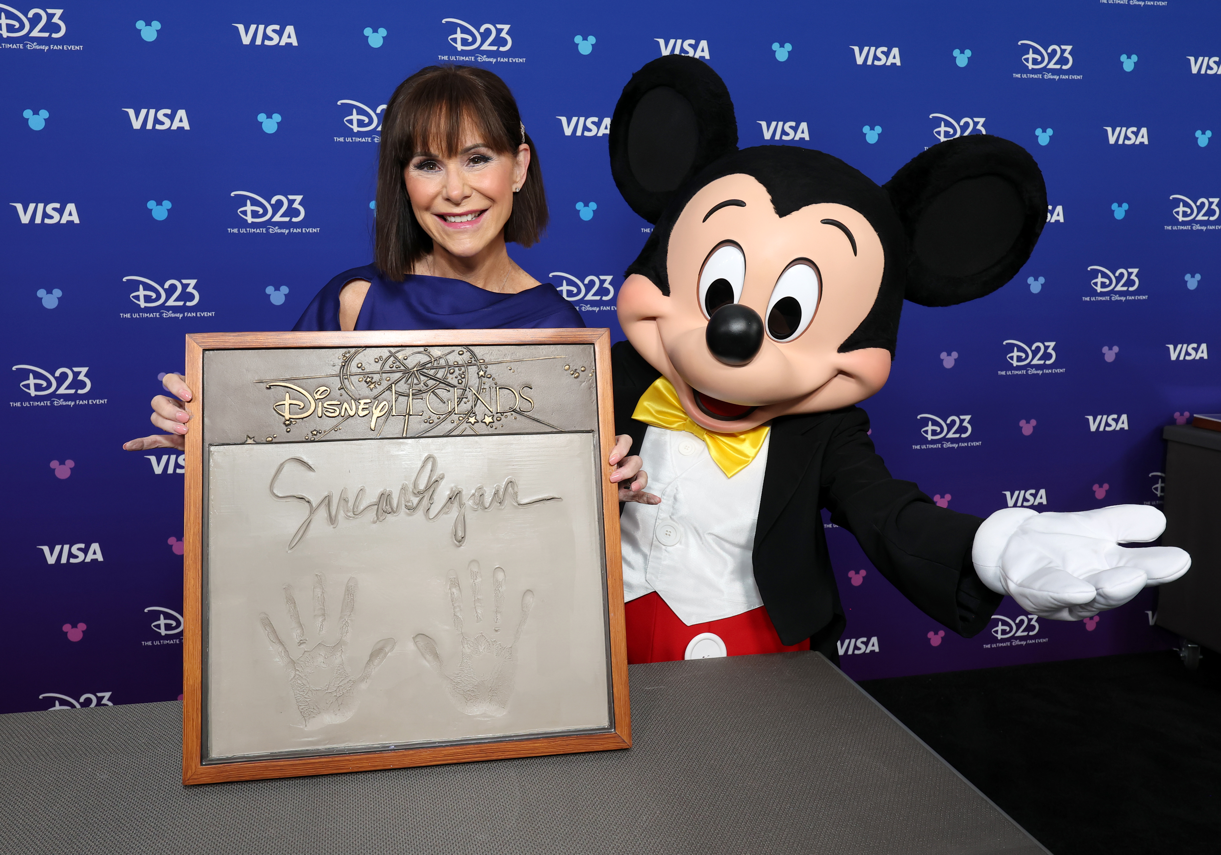 ANAHEIM, CALIFORNIA - AUGUST 16: Susan Egan gets her handprints with Mickey Mouse at the Disney Entertainment Showcase at D23: Legends on August 16, 2026 in Anaheim, California. (Photo by Kevin Mazur/Getty Images for Disney)