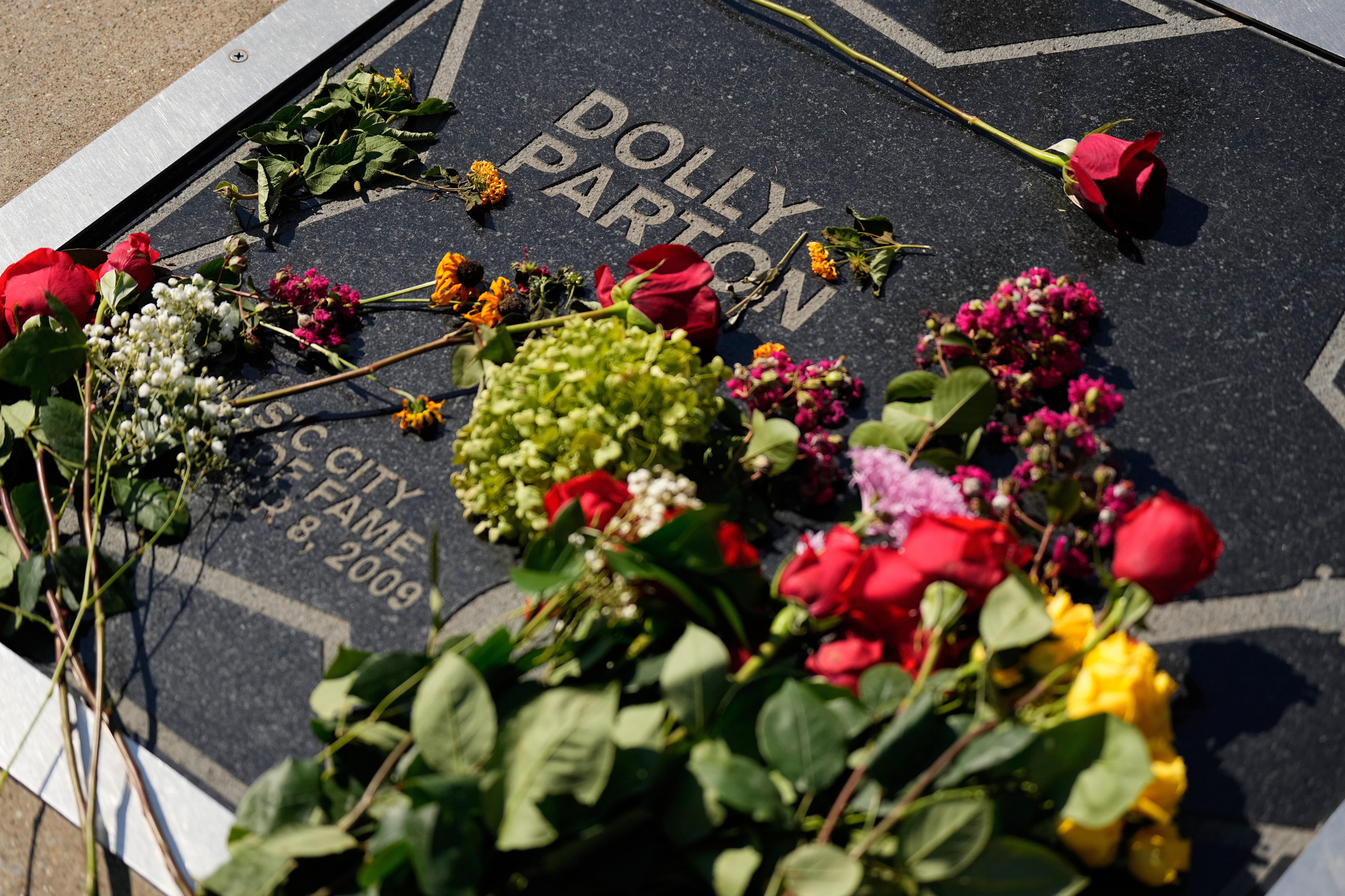Flowers lay on Dolly Parton's star on the Music City Walk of Fame outside the Country Music Hall of Fame on Tuesday, Aug. 25, 2026, in Nashville, Tenn. (AP Photo/George Walker IV)
