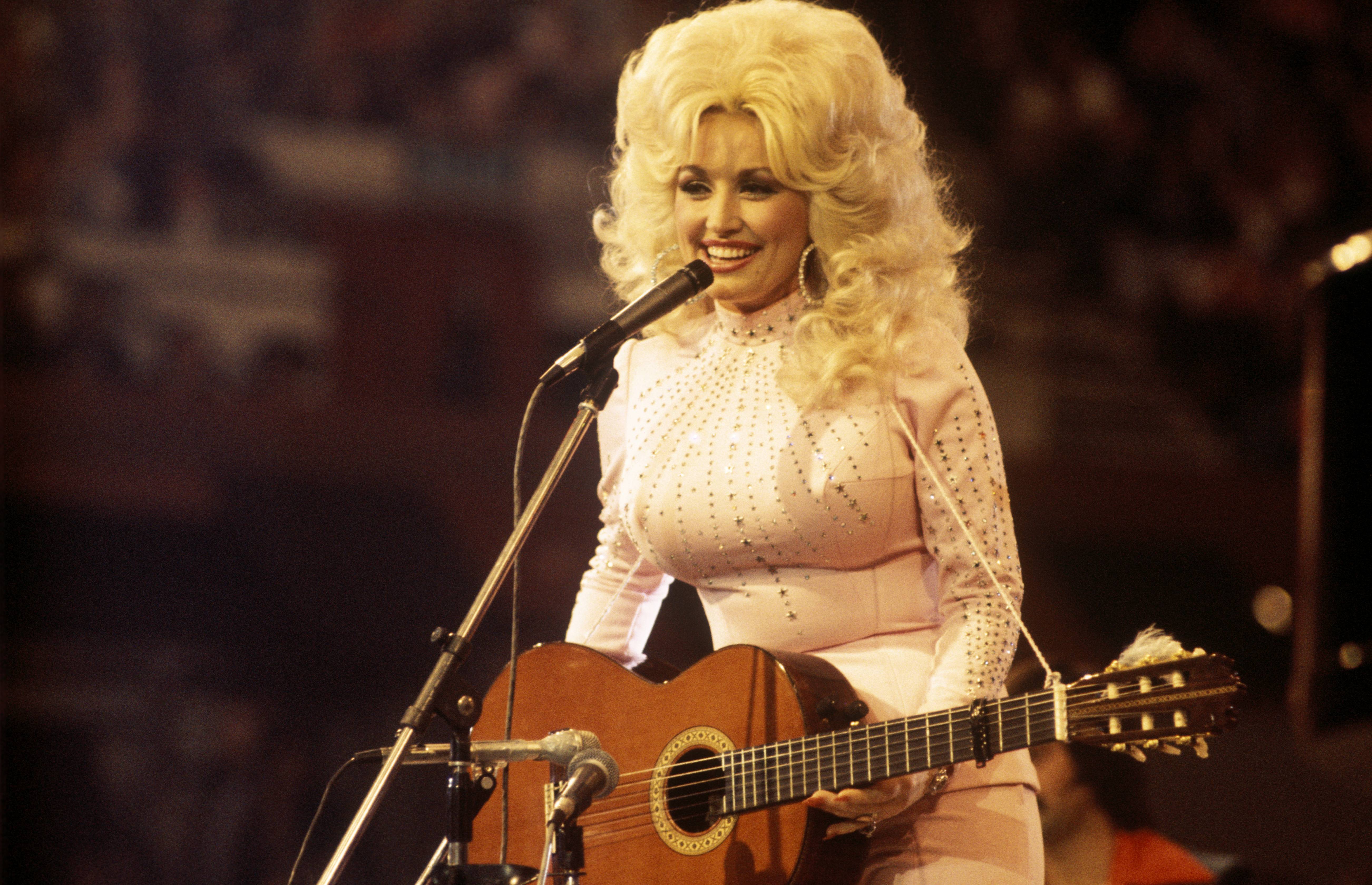 UNITED KINGDOM:  American singer, songwriter and actress Dolly Parton, performs with a guitar, 1976. (Photo by David Redfern/Redferns)
