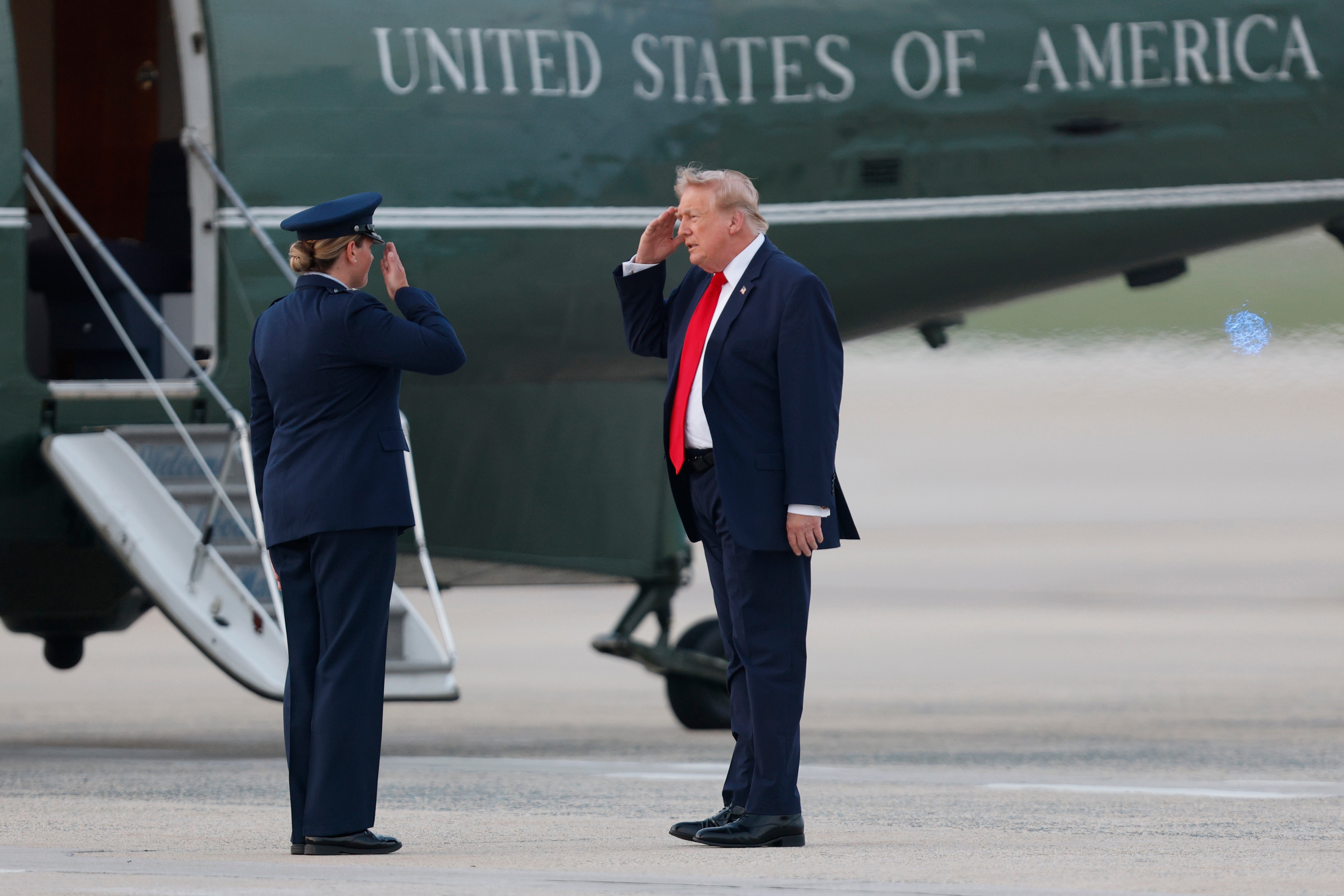 President Donald Trump, right, salutes Air Force 89th Air Wing Deputy Commander Melissa Dombrock, left, before boarding Marine One upon his arrival at Joint Base Andrews, Md., Sunday, July 19, 2026. (AP Photo/Luis M. Alvarez)