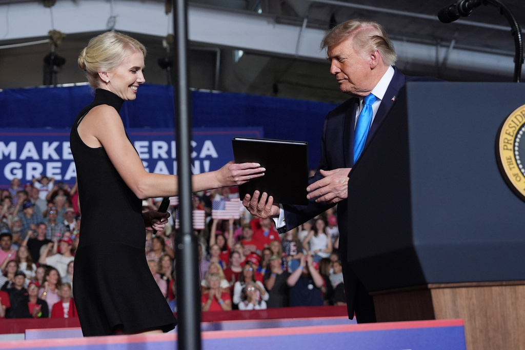 White House aide Natalie Harp hands an executive order to President Donald Trump at a campaign rally at the Pinnacle Bank Expo Center, Monday, Oct. 5, 2026, in Grand Island, Neb. (AP Photo/Alex Brandon)
