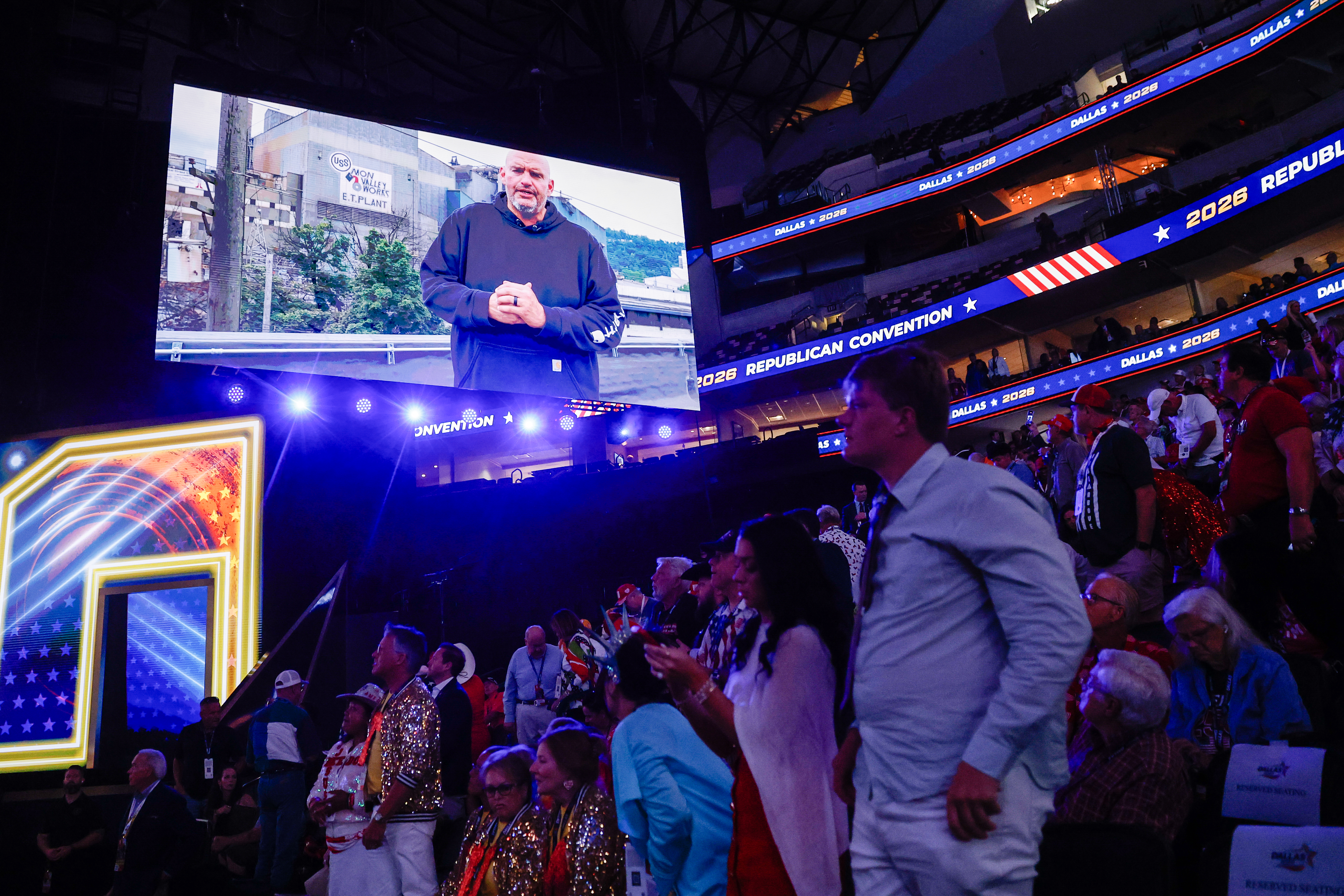 DALLAS, TEXAS - SEPTEMBER 09: People watch as U.S. Sen. John Fetterman (D-PA) appears on a video to endorse U.S. Sen. David McCormick (R-PA) on the first day of the 2026 Republican National Convention at the American Airlines Center on September 09, 2026 in Dallas, Texas. U.S. President Donald Trump will headline the Republican National Committee's first-ever midterm convention as he aims to highlight his administration’s achievements and rally support for GOP candidates just two months before the upcoming elections being held on November 3. (Photo by Justin Sullivan/Getty Images)