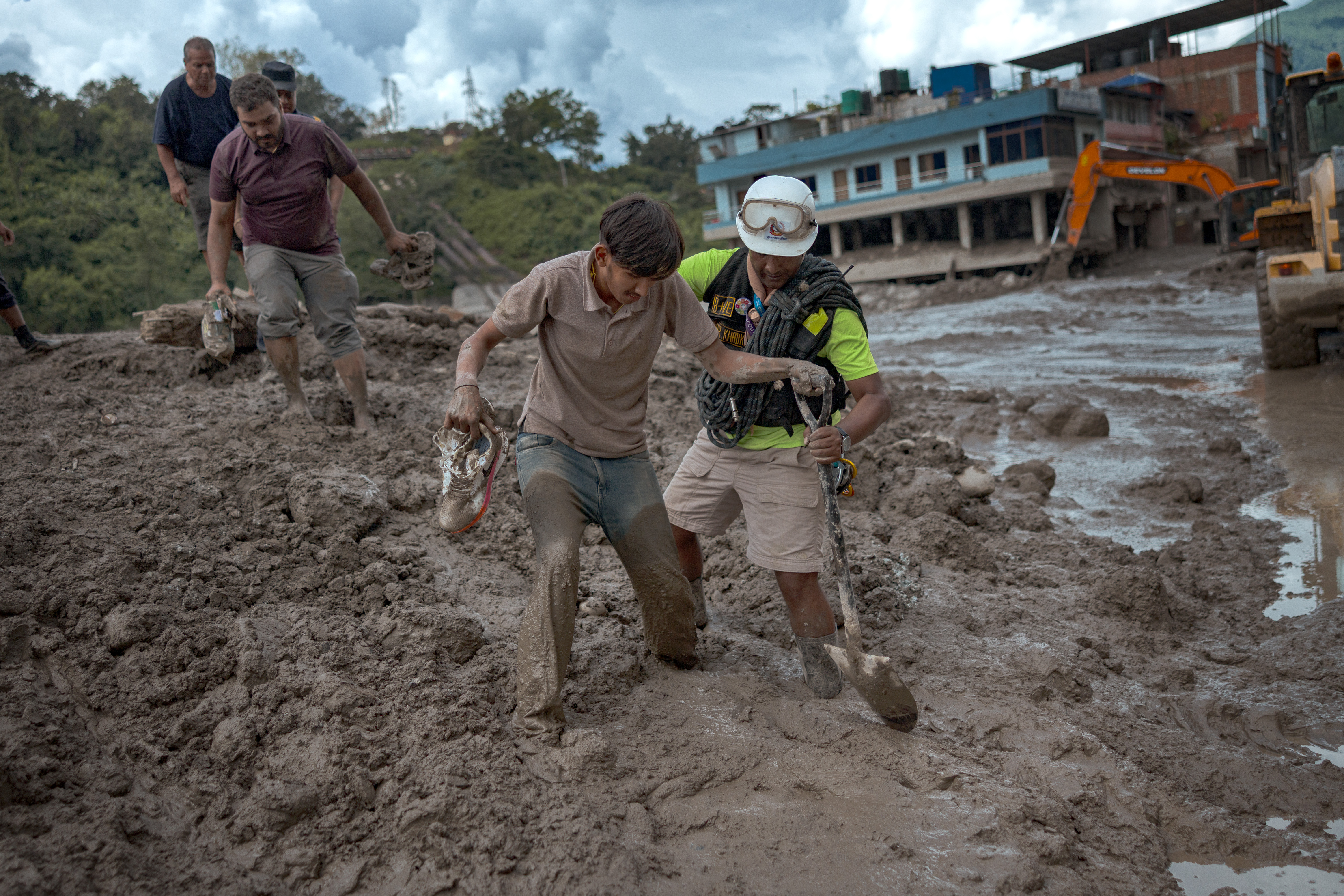 TRISHULI, NEPAL - AUGUST 27: A rescuer assists a resident through heavy mud following flash floods on August 27, 2026 in Trishuli, Nepal. A sudden flood swept through the Bhote Koshi River basin in northern Rasuwa on August 26, damaging settlements, roads and energy infrastructure as rescue teams searched for residents and foreign travellers reported out of contact. Hundreds were reported missing, as the death toll started to climb. (Photo by Ezra Acayan/Getty Images)