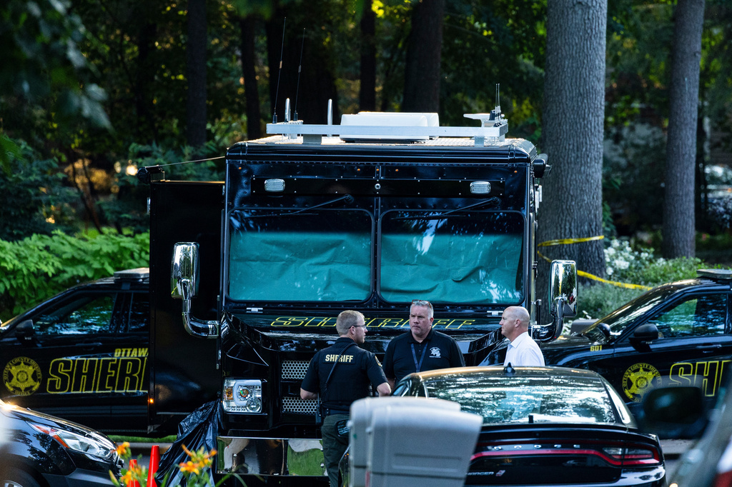 Law enforcement officials gather to investigate a fatal house fire on Friday, July 24, 2026, in Grand Haven Township, Mich. Ottawa County Sheriff's Office said six children and two adults were found dead in a