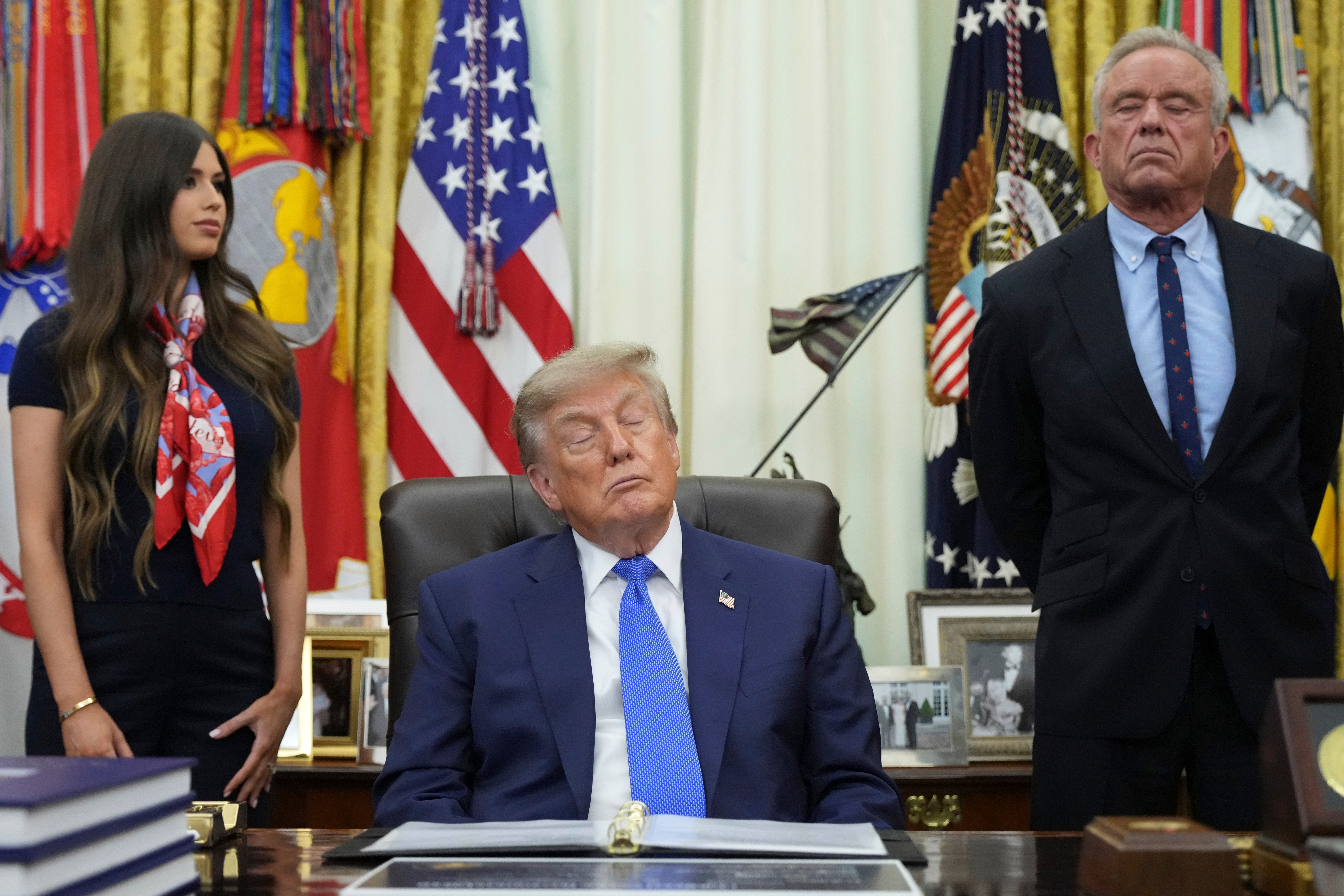President Donald Trump, center, Health and Human Services Secretary Robert F. Kennedy Jr., right, and Jayme Franklin listen during a meeting to sign an executive order about vaccines, Monday, Aug. 10, 2026, in the Oval Office of the White House in Washington. (AP Photo/Jacquelyn Martin)
