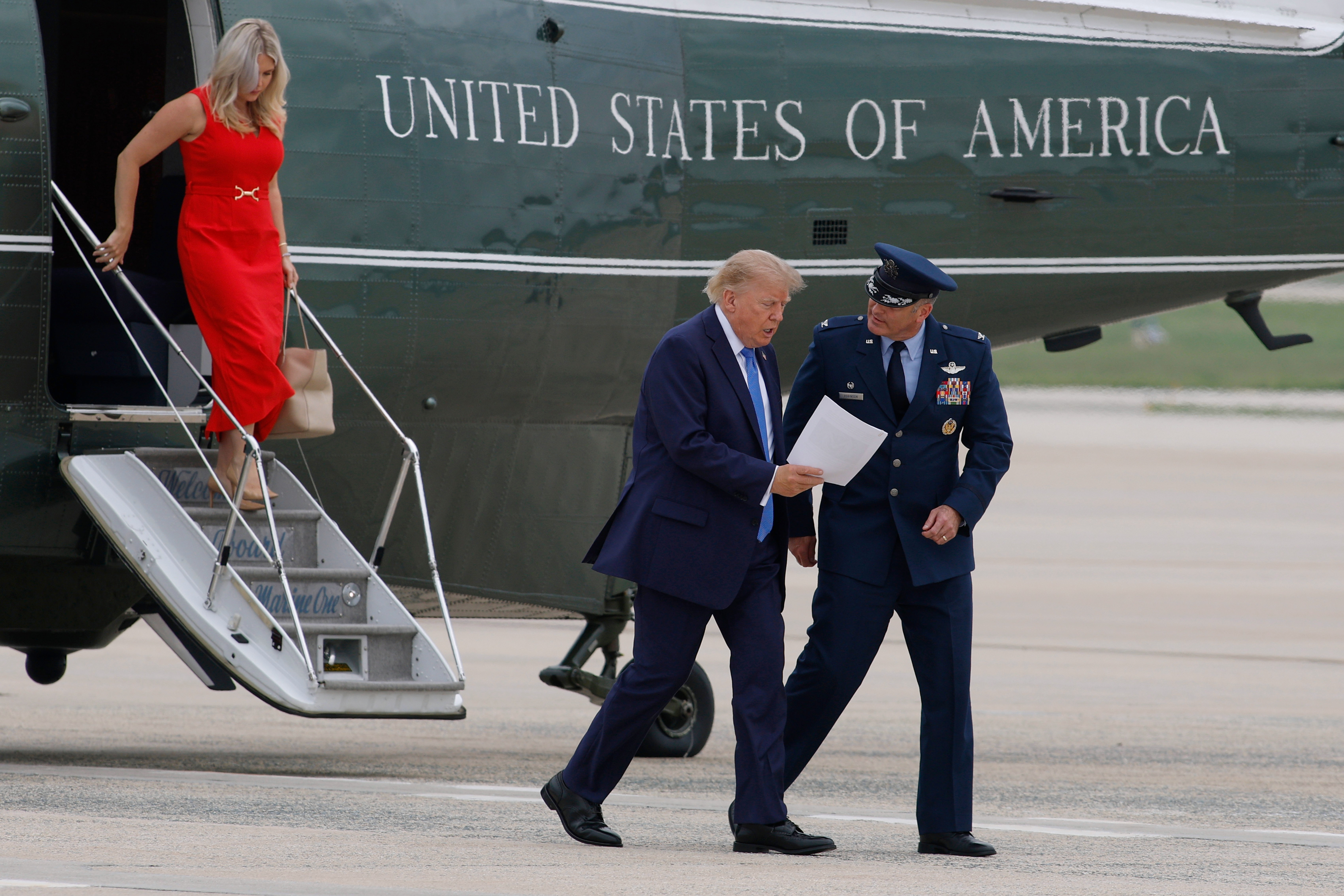President Donald Trump, center, is greeted by Air Force Col. Christopher M. Robinson, commander of the 89th Airlift Wing, right, as he and White House press secretary Karoline Leavitt, top left, walk from Marine One before boarding Air Force One, Friday, Aug. 14, 2026, at Joint Base Andrews, Md. (AP Photo/Luis M. Alvarez)