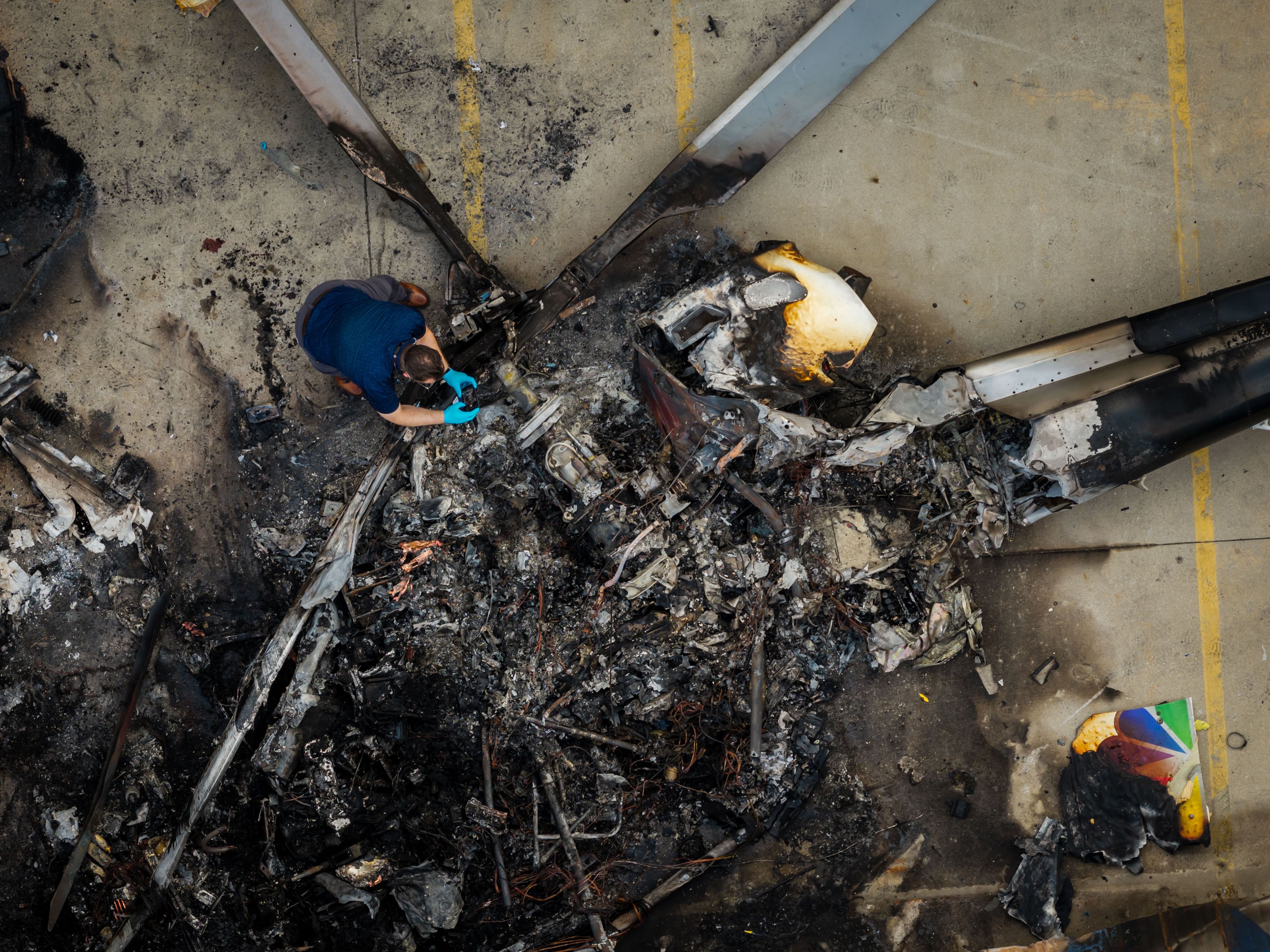 In this aerial view, people investigate the aftermath of a news helicopter crash in Chatsworth, a neighborhood in Los Angeles, on Wednesday, Sept. 16, 2026.(AP Photo/Ethan Swope)