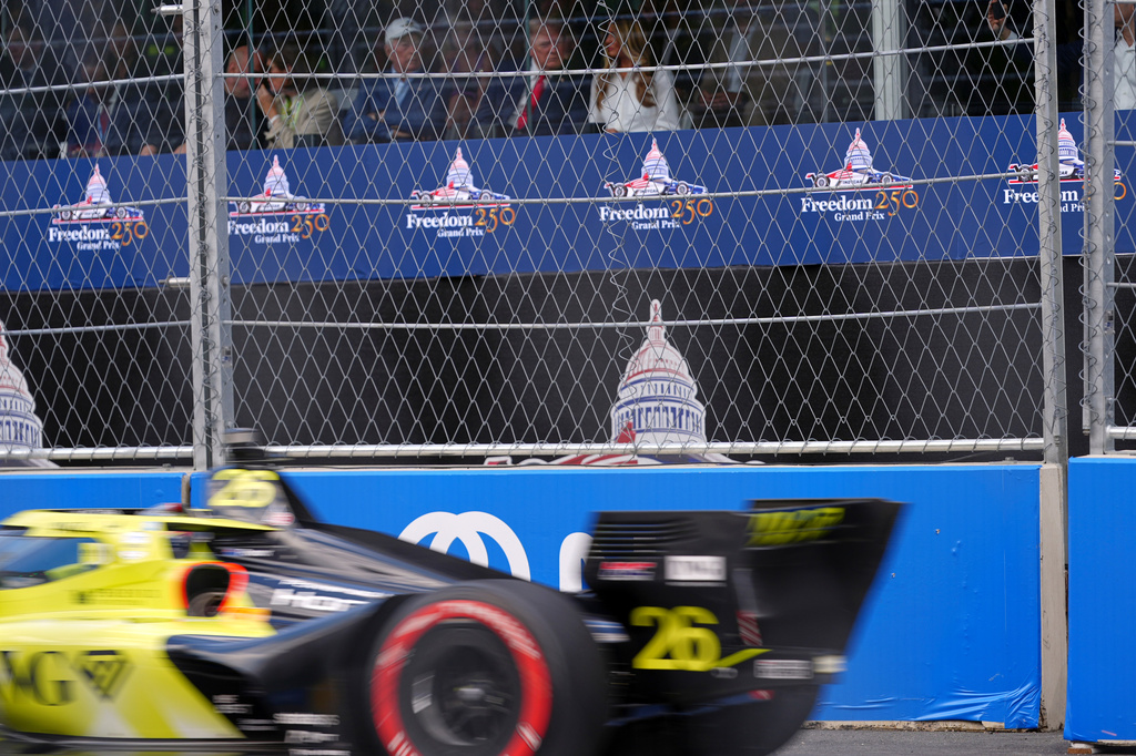 Will Power (26), of Australia, drives by as first lady Melania Trump, from right, President Donald Trump, Roger Penske, chairperson and founder of Penske Corp., Kathy Penske and UFC CEO Dana White watch the IndyCar Freedom 250 Grand Prix auto race, Sunday, Aug. 23, 2026, in Washington. (AP Photo/Julia Demaree Nikhinson)