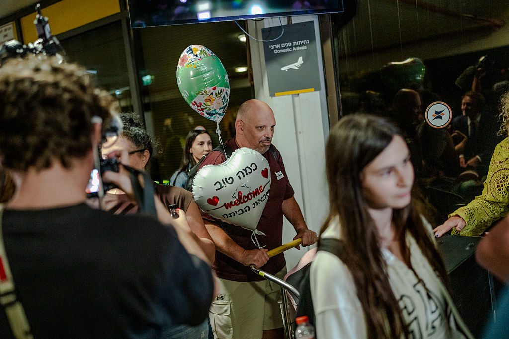 TZAFRIA, ISRAEL - SEPTEMBER 30: A passenger pushes a luggage cart holding welcome-home balloons through the arrivals area surrounded by relatives and cameras at Ben Gurion Airport on September 30, 2026 in Tzafria, Israel. This morning, a Flydubai flight from Dubai to Tel Aviv was diverted to Saudi Arabia after a violent altercation in the cockpit. Passengers told media outlets that a pilot was stabbed and temporarily lost control of the plane. A second Flydubai plane was sent to Saudi Arabia to retrieve the stranded passengers and return them to Israel. (Photo by Erik Marmor/Getty Images)