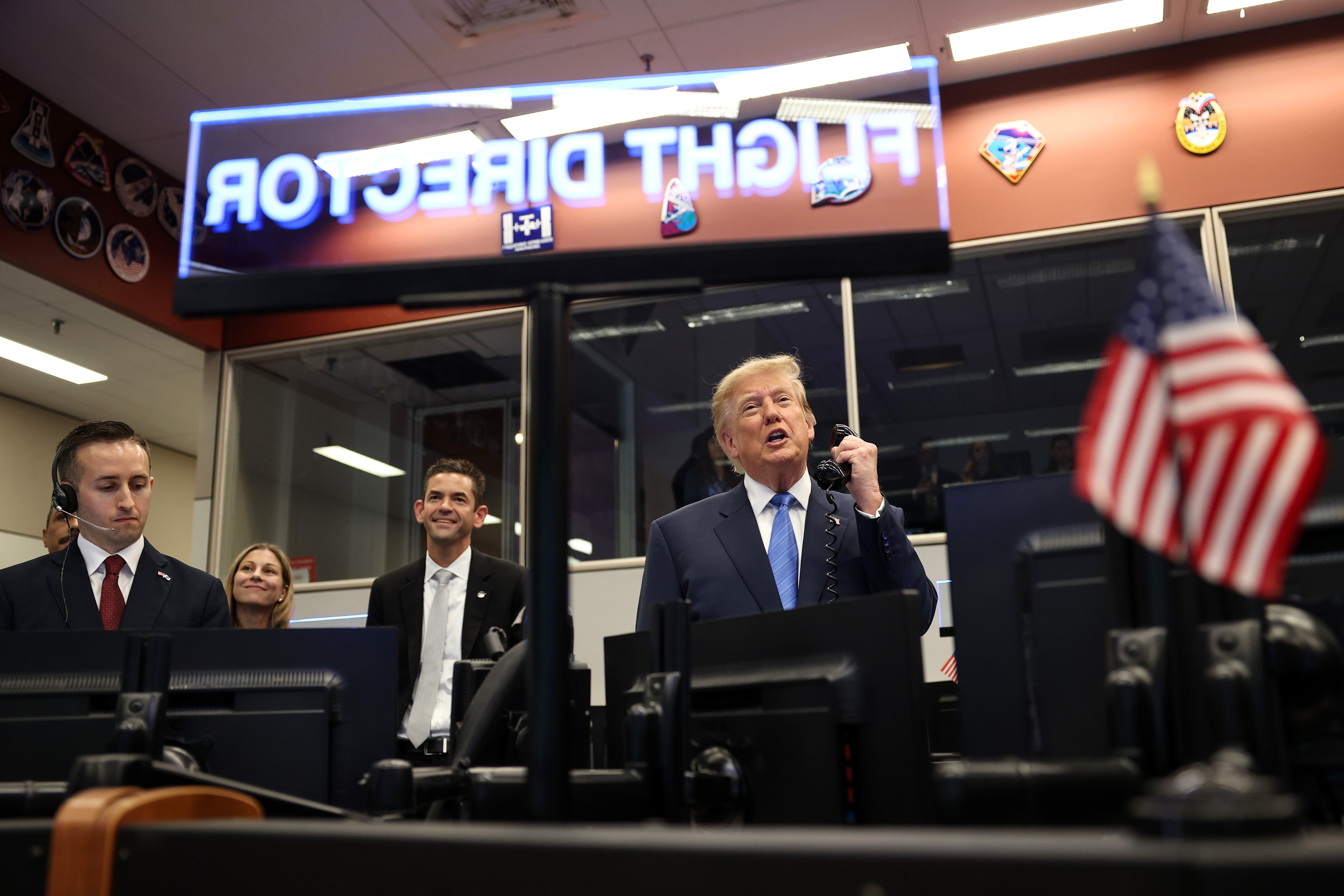 HOUSTON, TEXAS - AUGUST 28: U.S. President Donald Trump (R) speaks to astronauts aboard the International Space Station alongside National Aeronautics and Space Administration (NASA) Administrator Jared Isaacman (3rd-L) at NASA Mission Control Center​ following a ceremony honoring Artemis II crew members at Johnson Space Center on August 28, 2026 in Houston, Texas. Artemis II crew members, NASA astronauts Reid Wiseman, Victor Glover, and Christina Koch and Canadian astronaut Jeremy Hansen, traveled further into space than any other humans before on the first crewed mission around the moon in more than 50 years. (Photo by Win McNamee/Getty Images)