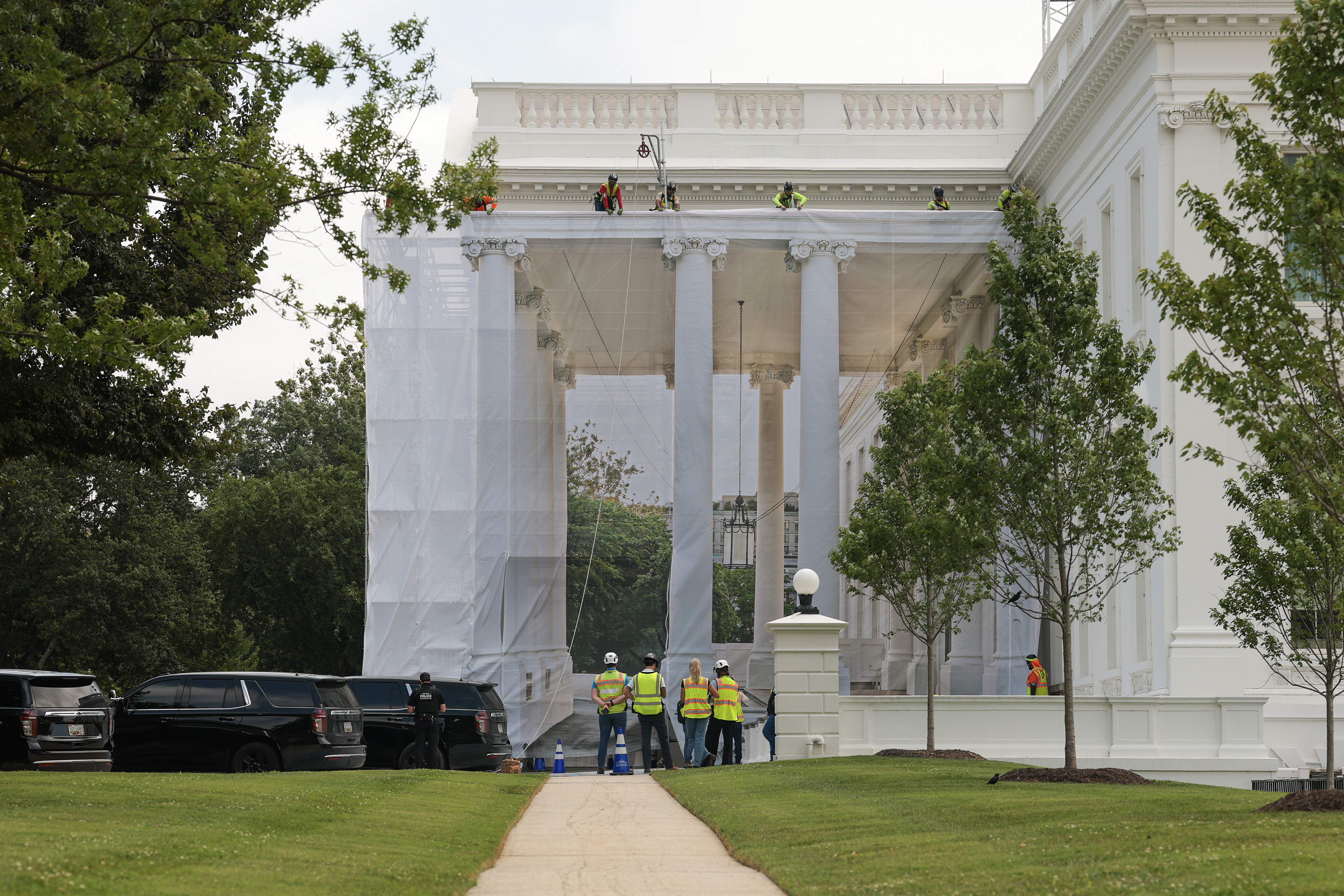 WASHINGTON, DC - JULY 09: Construction workers place a tarp over the scaffolding that surrounds the columns at the North Portico of the White House on July 09, 2026 in Washington, DC. U.S. President Donald Trump continues to do construction throughout the White House grounds. (Photo by Anna Moneymaker/Getty Images)