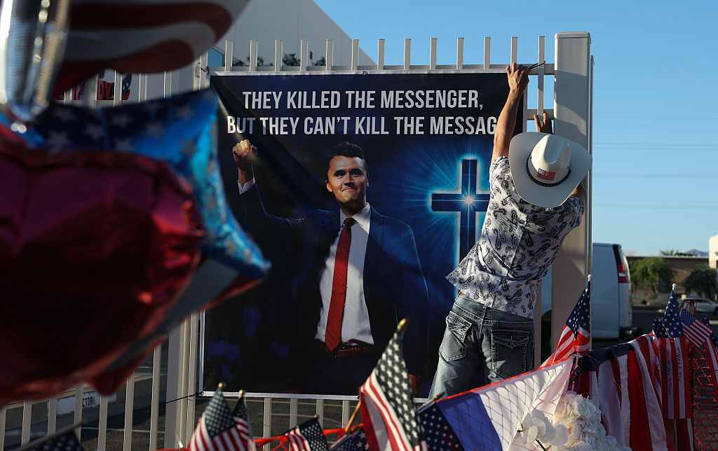 PHOENIX, ARIZONA - SEPTEMBER 19: Dr. T Tran places a poster up in the makeshift memorial for Charlie Kirk outside the headquarters of Turning Point USA on September 19, 2025, in Phoenix, Arizona. Kirk, the CEO and co-founder of Turning Point USA, was shot and killed on September 10th while speaking at an event for his