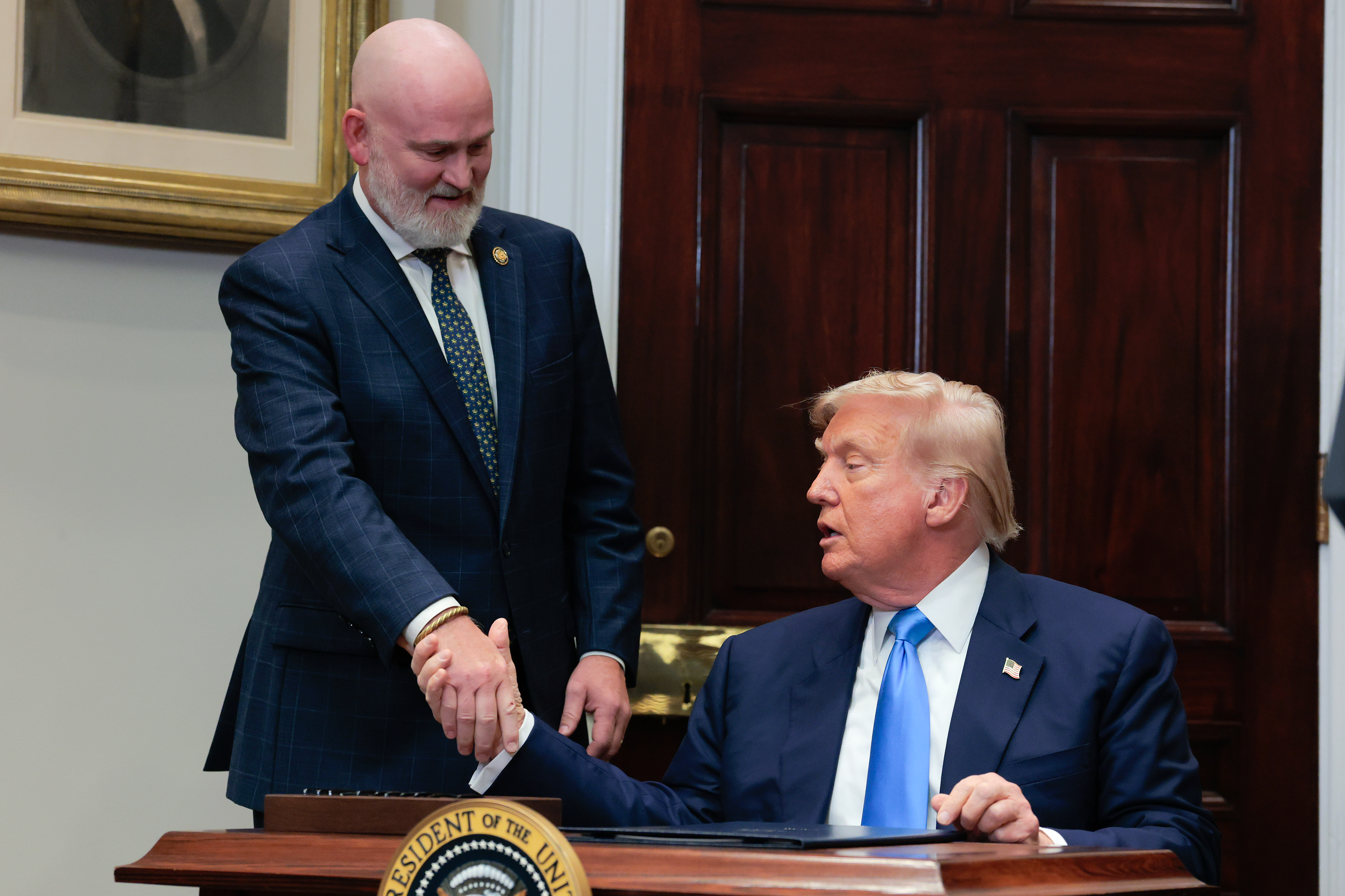 WASHINGTON, DC - JULY 30: U.S. President Donald Trump shakes hands with Rep. Derrick Van Orden (L) (R-WI) after he signed legislation creating a safety net for U.S. veterans and prevent them from potentially losing their homes in the Roosevelt Room of the White House on July 30, 2025 in Washington, DC. Trump signed the VA Home Loan Program Reform Act with members of Congress in attendance.  (Photo by Anna Moneymaker/Getty Images)