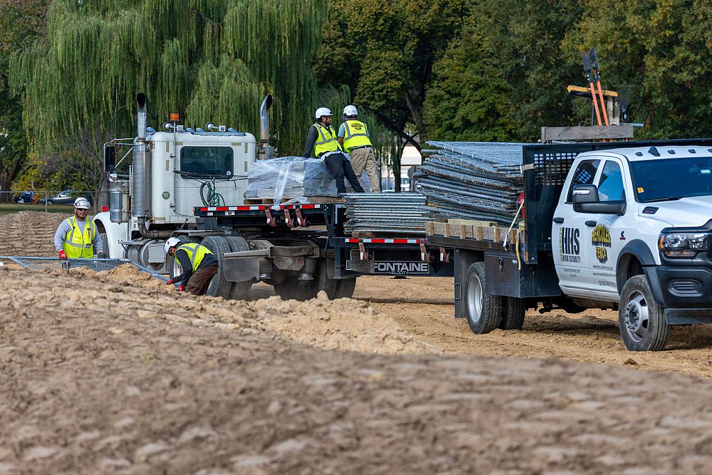 WASHINGTON, DC - OCTOBER 24: Workers build a fence as trucks unload debris and soil from the demolition of the White House's East Wing at East Potomac Golf Course on October 24, 2025 in Washington, DC. The demolition is part of U.S. President Donald Trump's plan to build a multimillion-dollar ballroom on the eastern side of the White House. (Photo by Tasos Katopodis/Getty Images)