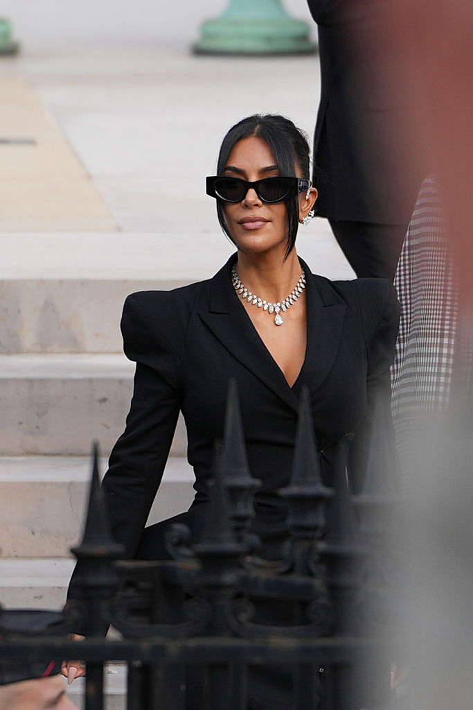 PARIS, FRANCE - MAY 13: Kim Kardashian exits the trial at the Palais de Justice, and wears sunglasses by Alaia, a black dress designed as a double breasted gathered blazer jacket with power shoulders / shoulder pads / puff shoulders and low-neck by John Galliano, a necklace by Samer Halimeh, Repossi diamond earcuffs, Brioni Raymond earrings, at the Palais de Justice, on May 13, 2025 in Paris, France. (Photo by Edward Berthelot/GC Images)