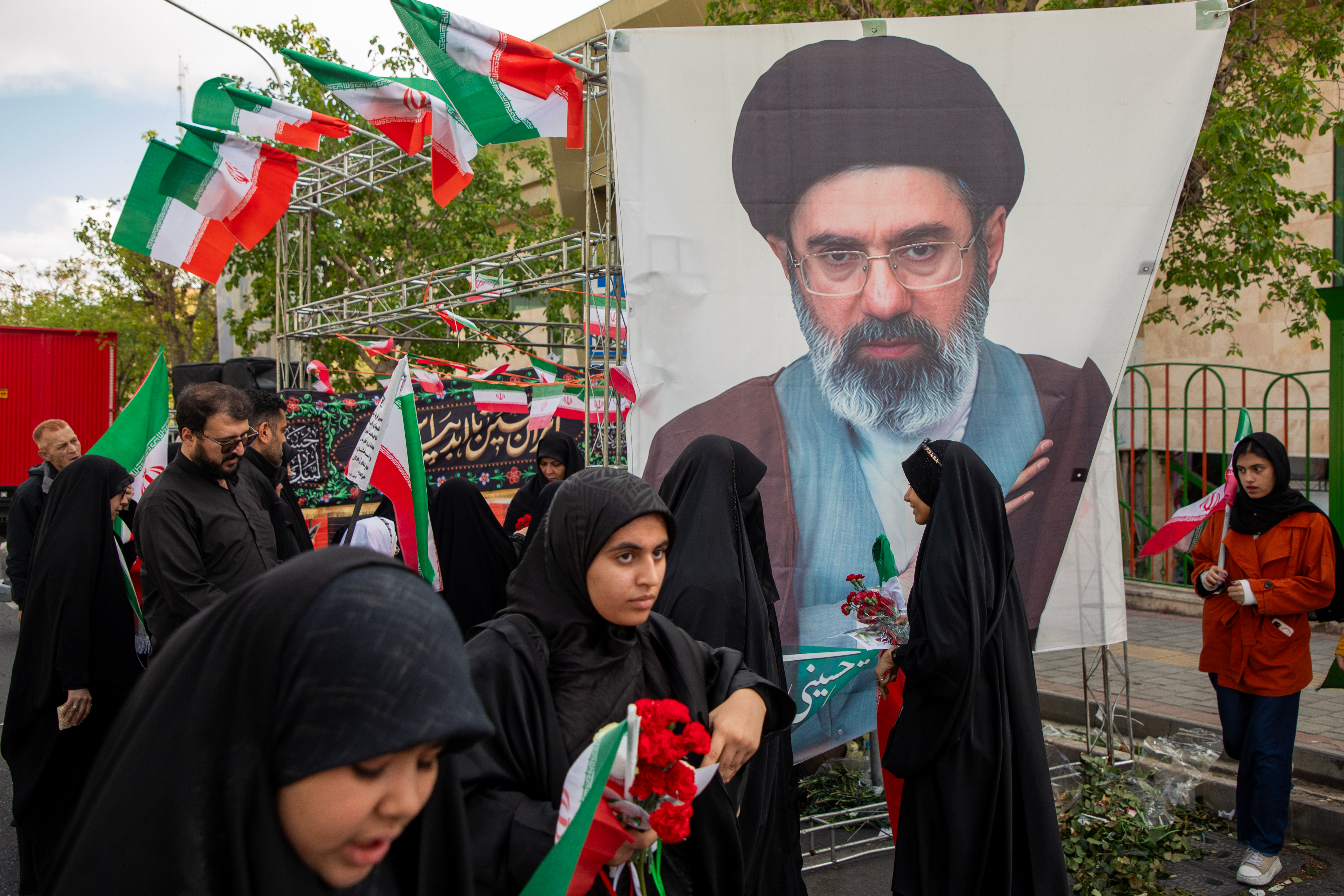 TEHRAN, IRAN - APRIL 7: People gather in front of a portrait of Iran's new Supreme Leader, Mojtaba Khamenei, son of the late Supreme Leader, Ayatollah Ali Khamenei, during a memorial marking 40 days since a strike in the southern Iranian town of Minab killed at least 168 people, including around 110 children, on April 7, 2026, in downtown Tehran, Iran. US Defence Secretary Pete Hegseth has said the incident is being investigated, while US media have reported that, according to military investigators, the strike carried out by US forces unintentionally targeted the school using outdated satellite imagery. (Photo by Majid Saeedi/Getty Images)