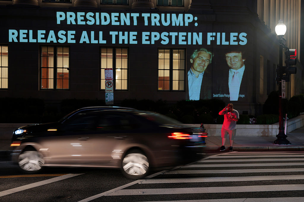 WASHINGTON, DC - JULY 18: A person crosses the street near an image of U.S. President Donald Trump and Jeffrey Epstein, along with the words “President Trump: Release All the Epstein Files”, projected onto the U.S. Chamber of Commerce building on July 18, 2025, in Washington, D.C. Earlier today, the Department of Justice asked federal judges to unseal files in the criminal cases of Jeffrey Epstein and Ghislaine Maxwell. (Photo by Anna Moneymaker/Getty Images)