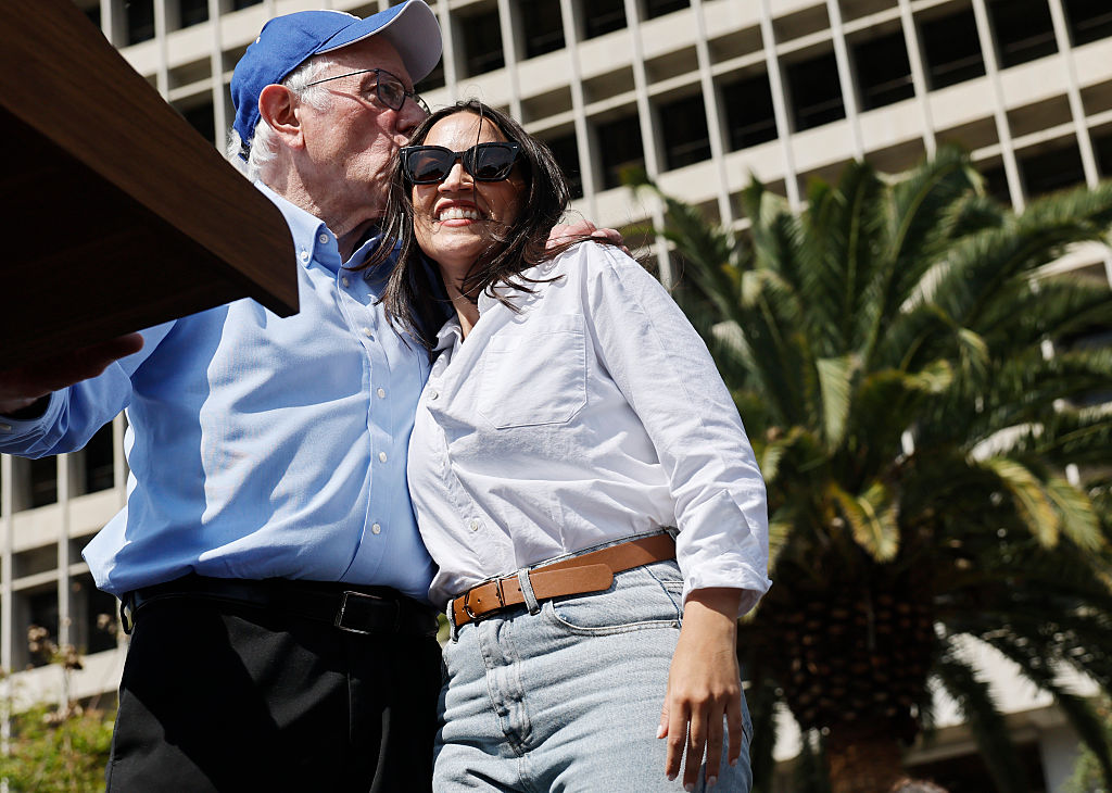 LOS ANGELES, CALIFORNIA - APRIL 12: U.S. Sen. Bernie Sanders (I-VT) and Rep. Alexandria Ocasio-Cortez (D-NY) embrace during a stop on their ‘Fighting Oligarchy’ tour at Grand Park on April 12, 2025 in Los Angeles, California. An estimated 36,000 people attended the rally which also saw Neil Young and Joan Baez perform.   (Photo by Mario Tama/Getty Images)