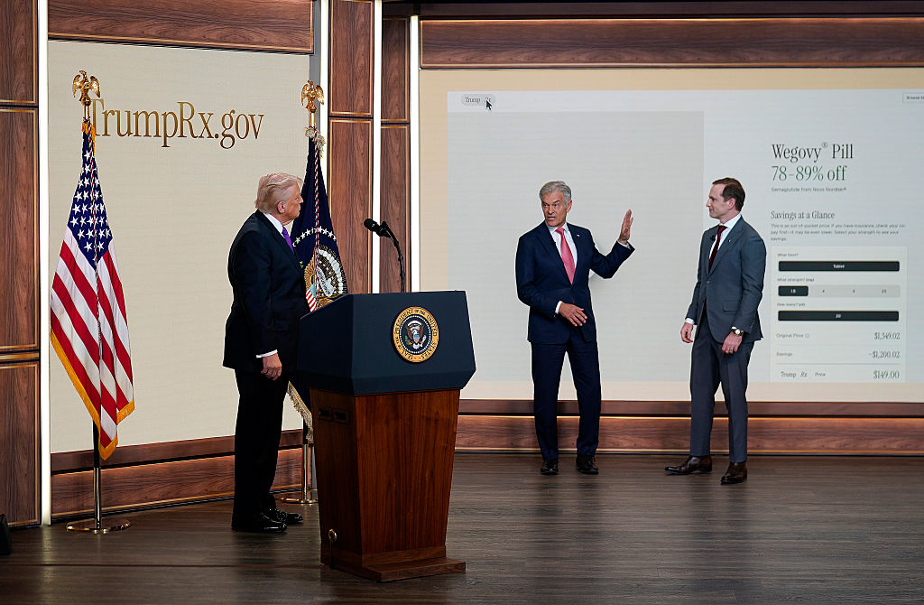 WASHINGTON, DC - FEBRUARY 5: Administrator for the Centers for Medicare & Medicaid Services Mehmet Oz (C) speaks as U.S. President Donald Trump (L) and Chief Design Officer of the National Design Studio Joe Gebbia look on during an event on drug pricing in the South Court Auditorium on the White House campus on February 5, 2026 in Washington, DC. The president announced the launch of TrumpRx, which the White House said would help lower prescription drug prices. (Photo by Nathan Howard/Getty Images)