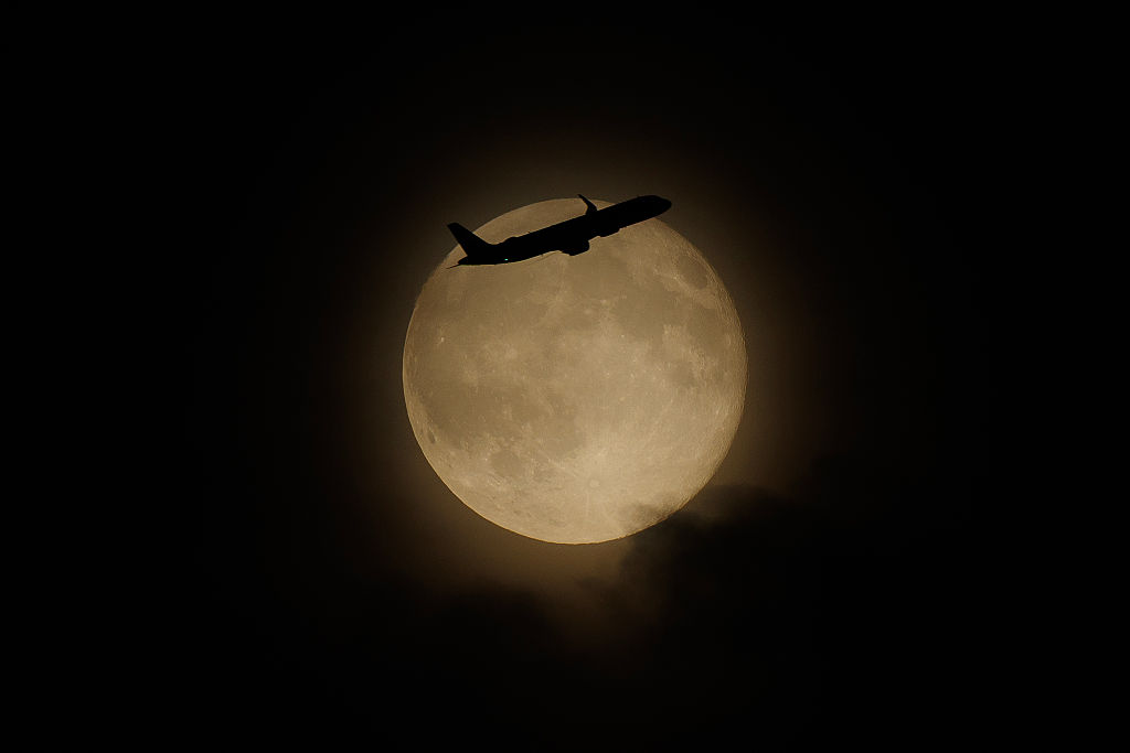 A plane flies in front of the harvest moon on October 7, 2025 in London, England. (Photo by Dan Kitwood/Getty Images)