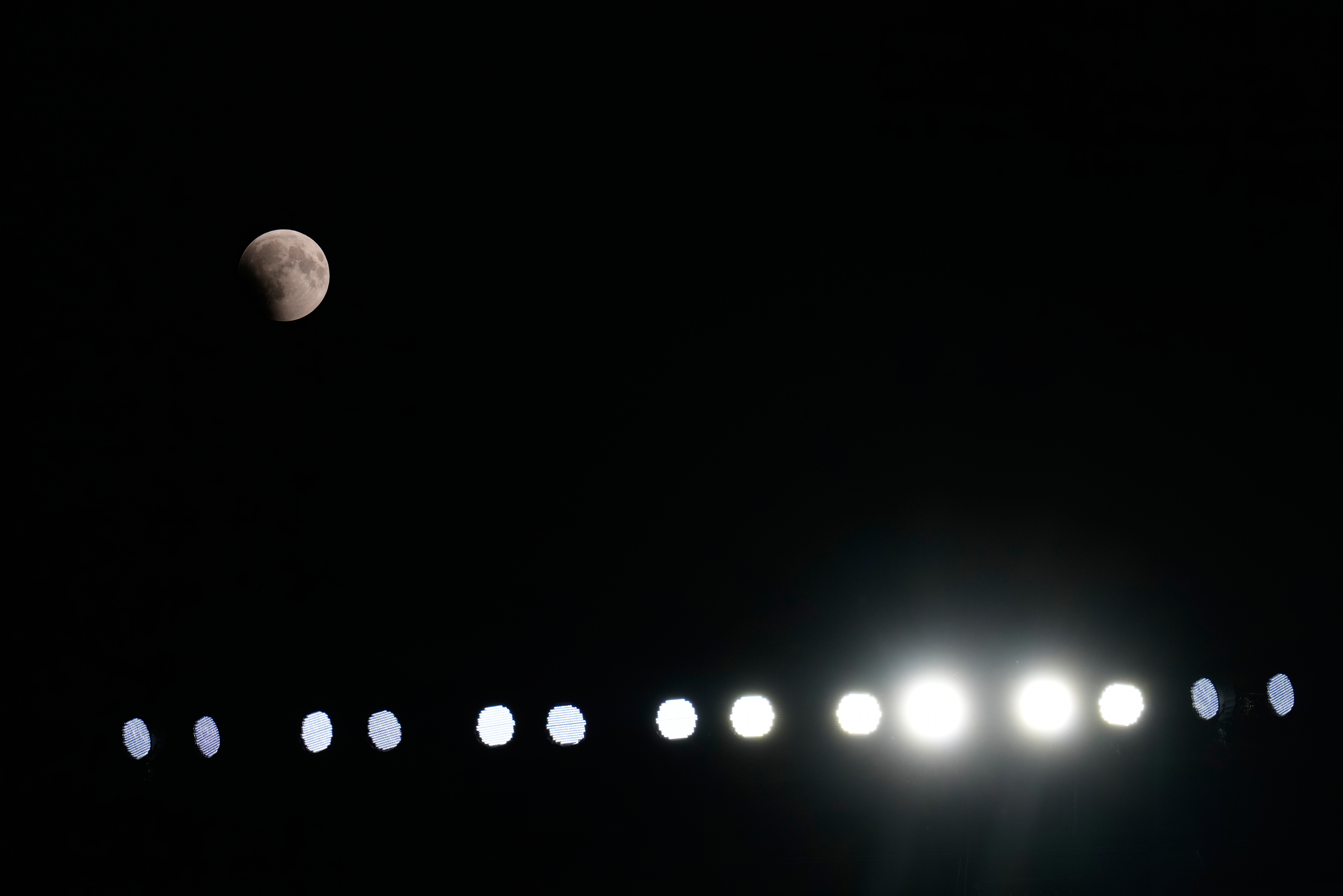 A partial lunar eclipse is seen above the stadium lights during the second half of a preseason NFL football game between the New England Patriots and Cleveland Browns Thursday, Aug. 27, 2026, in Cleveland. (AP Photo/Carolyn Kaster)