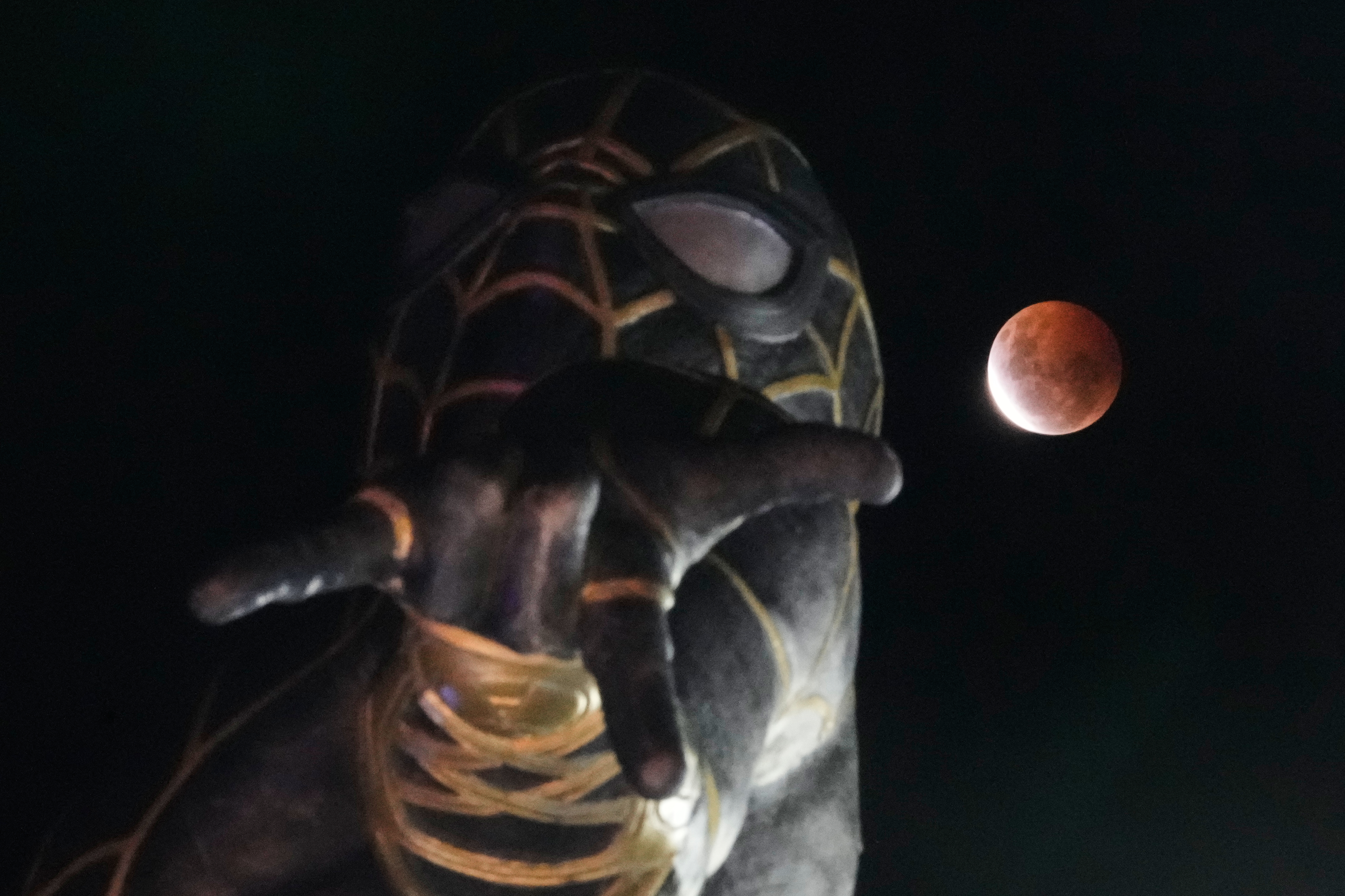 The moon rises behind a Spider-Man statue during a partial lunar eclipse in El Alto, Bolivia, Friday, Aug. 28, 2026. (AP Photo/Juan Karita)