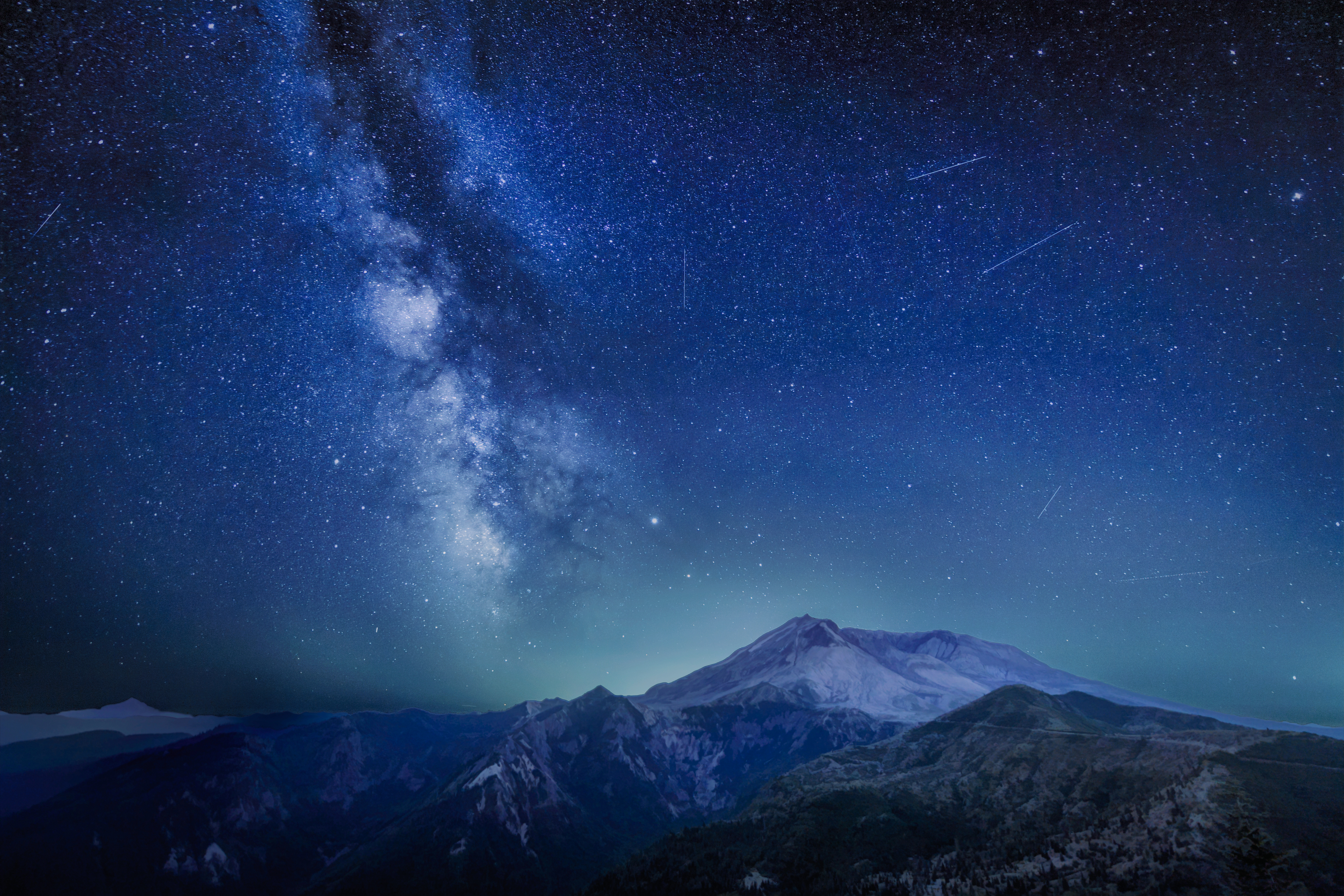 The Delta Aquariids meteor shower and Milky Way over Mount St. Helens, at Windy Ridge in Washington State with Mt. Hood, Oregon visible in the lower left corner.  Portland, Oregon is fifty miles to the south as you can tell by the ambient light behind Mount St. Helens.