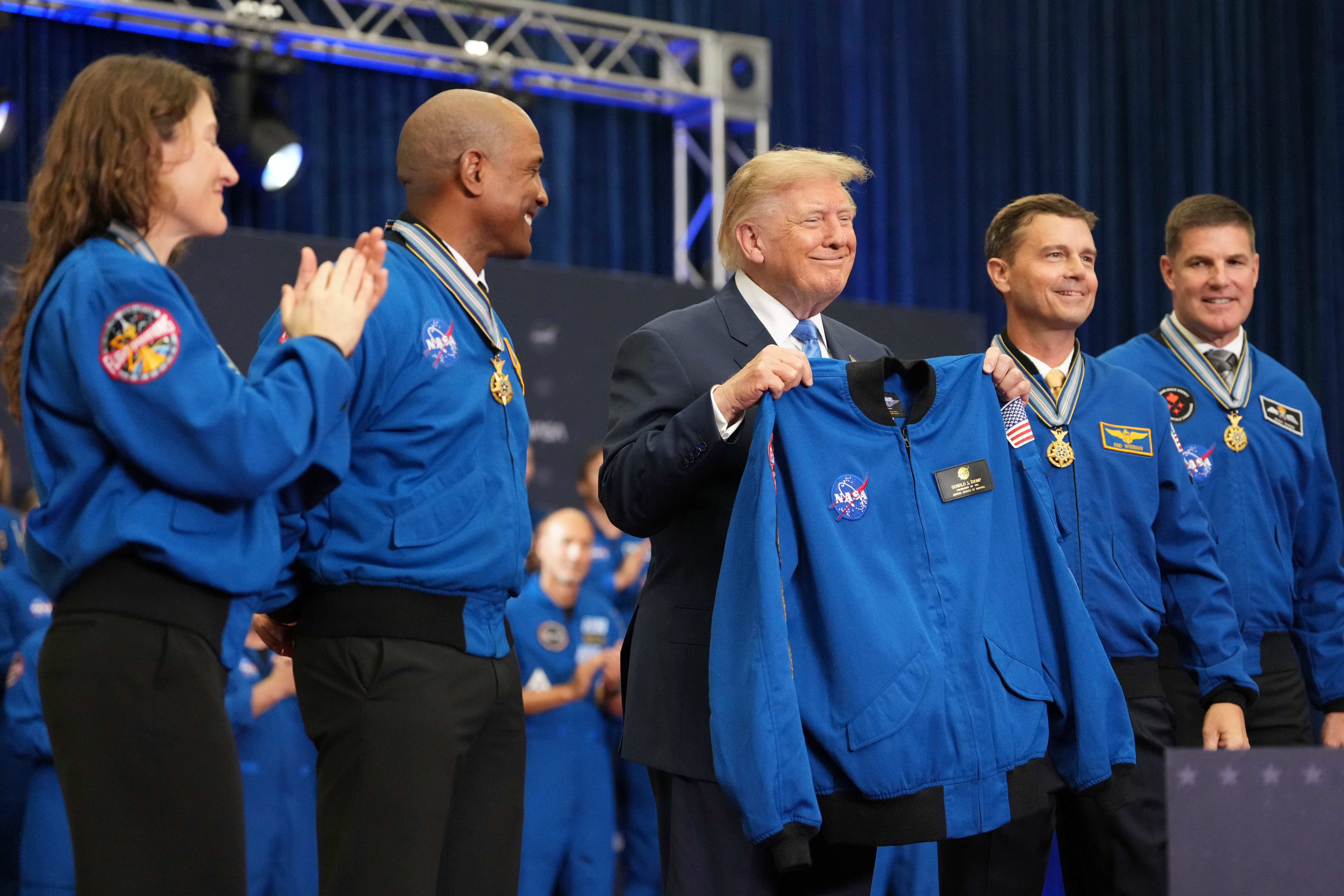 President Donald Trump holds up a flight jacket presented to him by Artemis II crew members Christina Koch, from left, Victor Glover, Reid Wiseman and Jeremy Hansen after the crew accepted the Congressional Space Medal of Honor, Friday, Aug. 28, 2026, at Johnson Space Center in Houston. (AP Photo/Mark Schiefelbein)
