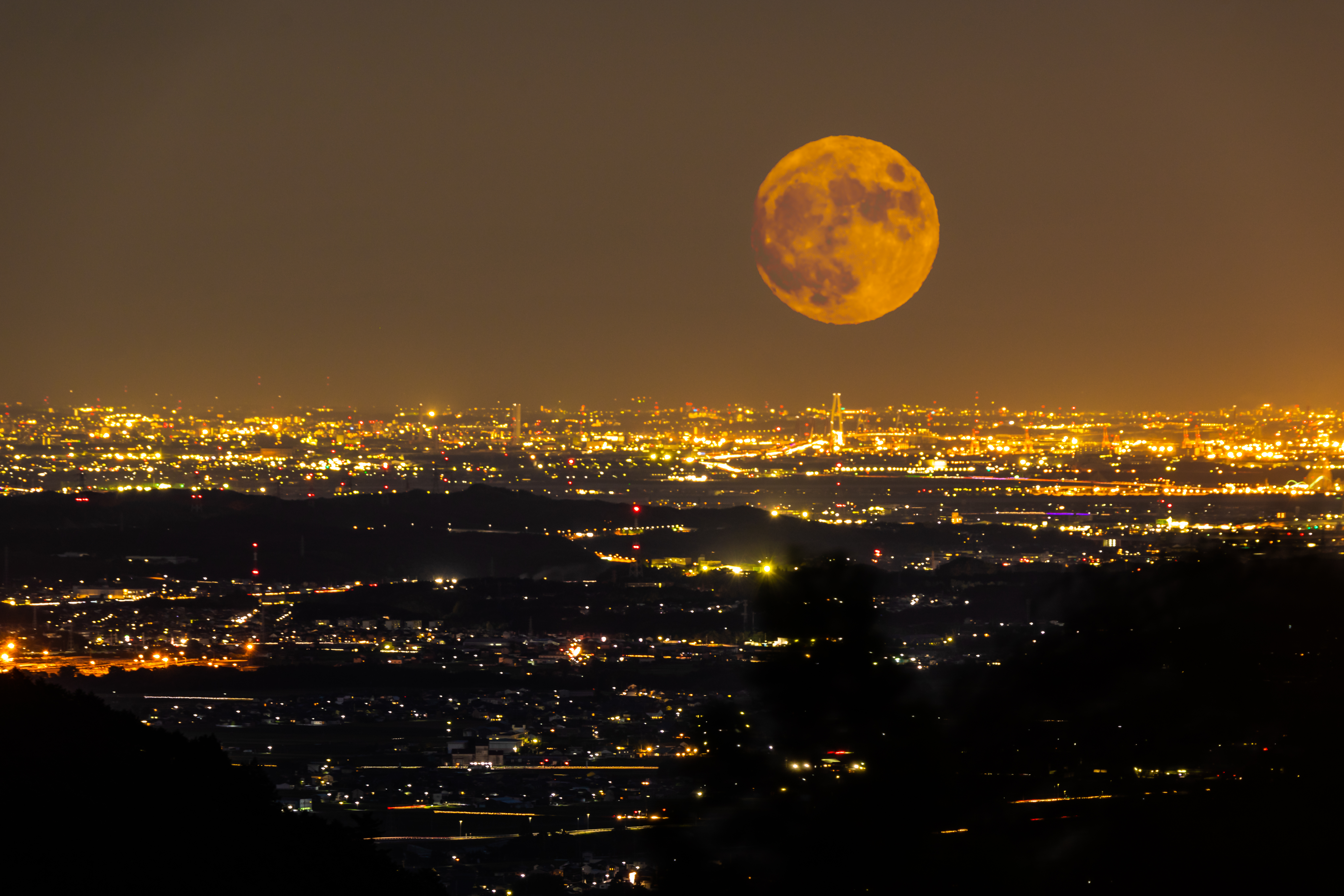 The view from Yunoyama onsen village in Komono. A big orange harvest moon rise over Yokkaichi city in Mie prefecture, Japan.