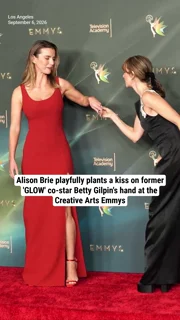 Alison Brie playfully plants a kiss on former 'GLOW' co-star Betty Gilpin's hand at the Creative Arts Emmys