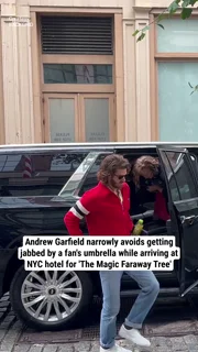 Andrew Garfield narrowly avoids getting jabbed by a fan's umbrella while arriving at NYC hotel for 'The Magic Faraway Tree'
