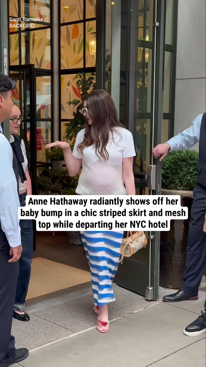 Anne Hathaway radiantly shows off her baby bump in a chic striped skirt and mesh top while departing her NYC hotel